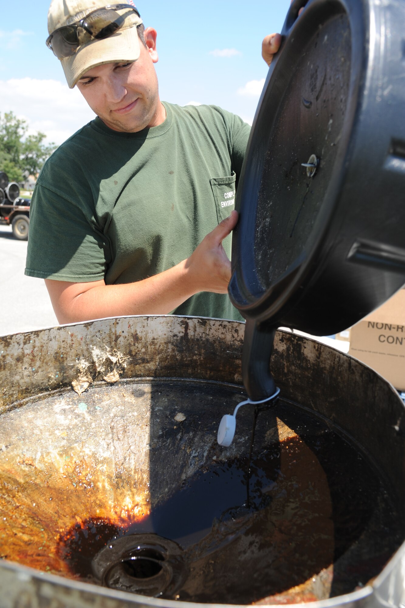 Travis Smith, Complete Environmental and Remediation Co., LLC technician, disposes oil in a barrel during a hazardous household waste collection event Aug. 29, 2013, at the Bay Breeze Event Center parking lot, Keesler Air Force Base, Miss.  The event was hosted by the base environmental office.  (U.S. Air Force photo by Kemberly Groue)