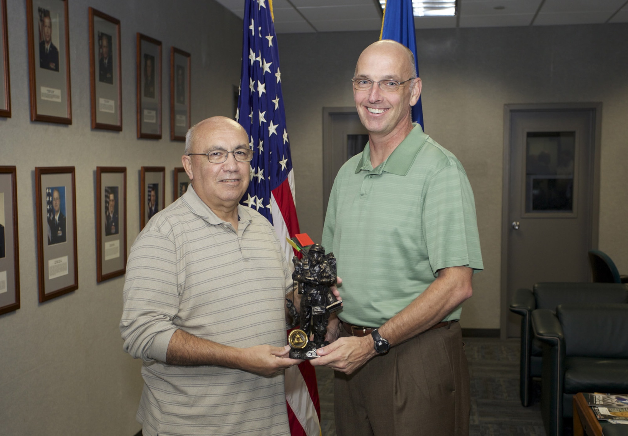 TYNDALL AIR FORCE BASE, Fla. - From right, Mike Connors, emergency management division chief at Det. 1, Air Force Civil Engineer Center here presents Tom Santiago, creator of Smokey Joe, with a commemorative statue bearing the character’s likeness Aug. 1, 2013. Smokey Joe has been the unofficial icon of Air Force Emergency Management for almost 30 years. (U.S. Air Force photo/Eddie Green)