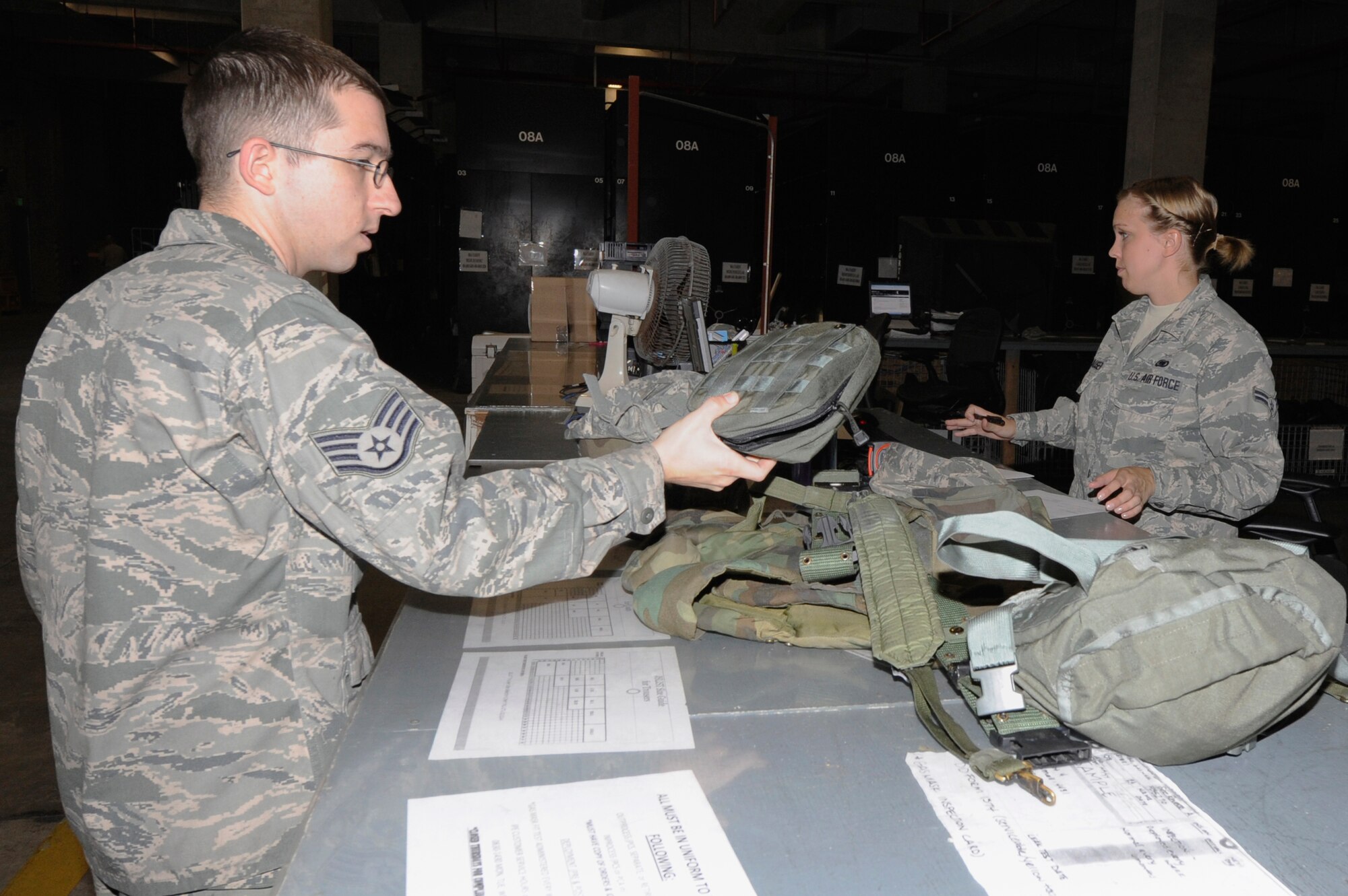 U.S. Air Force Staff Sgt. Kevin McCormack, 18th Aircraft Maintenance Squadron propulsion specialist, returns mission individual protection equipment to Airman 1st Class Jennifer Damhauser, 18th Logistics Readiness Squadron IPE technician, on Kadena Air Base, Japan, Nov. 26, 2013. IPE technicians maintain the shelf life of more than 27,000 items, complete gas mask leak tests and issue MOPP gear. (U.S. Air Force photo by Senior Airman Marcus Morris)