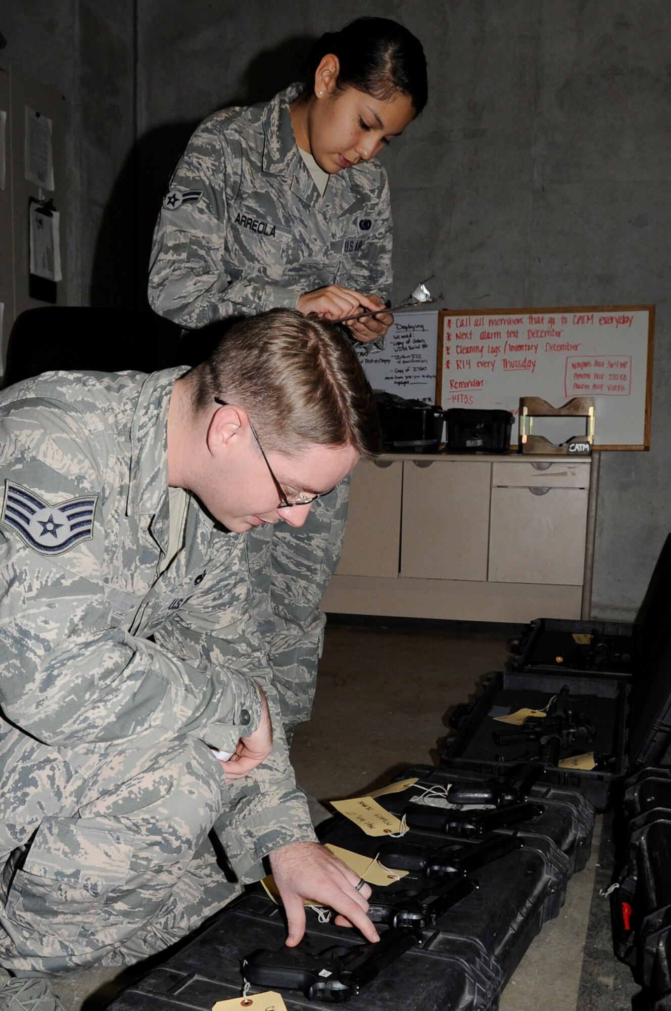 U.S. Air Force Staff Sgt. Joshua Pay, 718th Aircraft Maintenance Squadron unit readiness manager, verifies a serial number on an M-4 rifle to Airman 1st Class Rosa Arreola, 18th Logistic Readiness Squadron individual protection equipment technician, on Kadena Air Base, Japan, Nov. 21, 2013. The IPE technicians issue mobility bags and weapons to Airmen for local operational readiness exercises and real-world deployments. (U.S. Air Force photo by Senior Airman Marcus Morris)