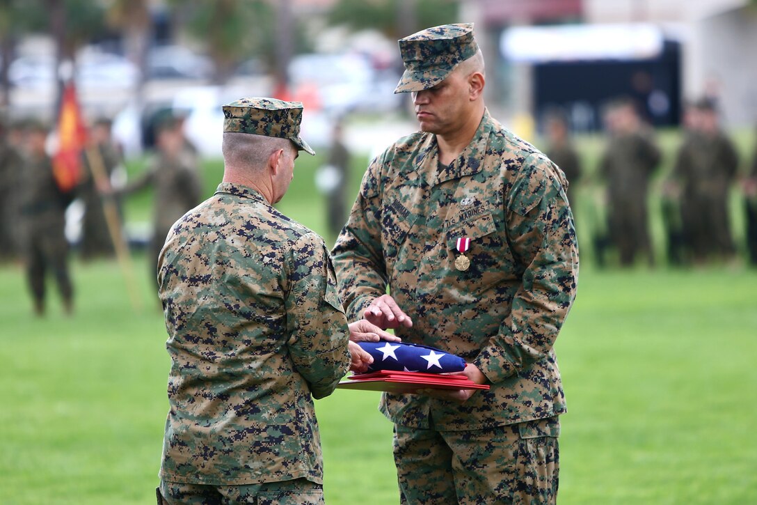 Master Gunnery Sgt. Kelly B. Norman, right, communications chief, Communications Company, Combat Logistics Regiment 17, 1st Marine Logistics Group, receives the American Flag from Col. Erik B. Kraft, commanding officer, CLR-17, during his retirement ceremony aboard Camp Pendleton, Calif., Nov. 20. His uncle, Reverend Dr. E.I. Norman, a World War II veteran and Montford Point Marine, attended the event and was honored during the ceremony. Master Gunnery Sgt. Norman served in the Corps for 30 years and is a native of Reading, Pa.