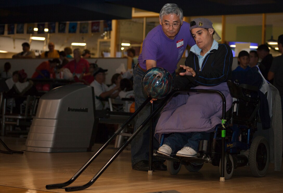 Yukio Hamada (left), a Special Olympics Hawaii volunteer, assists an athlete in rolling her bowling ball during a single’s bowling competition at K-Bay Lanes aboard Marine Corps Base Hawaii, Nov. 23, 2013. The bowling competition was part of the nonprofit organization’s annual Holiday Classic, a two-day event that was held at facilities aboard both MCB Hawaii and Joint Base Pearl Harbor-Hickam. (U.S. Marine Corps photo by Lance Cpl. Matthew Bragg)