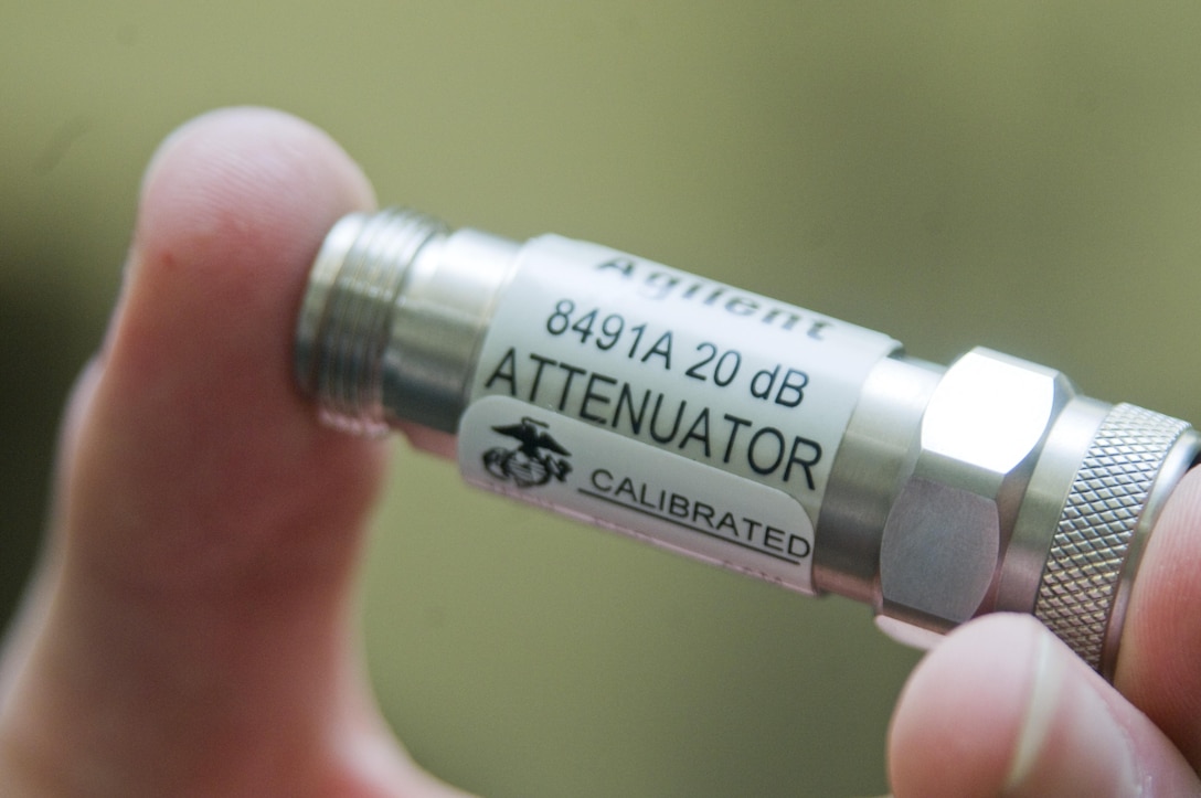 Sgt. Dillon McDonough, a quality assurance representative with Combat Logistics Company 35, holds up a 20-decibel cable attenuator verified as calibrated and working properly. (U.S. Marine Corps photo by Christine Cabalo)