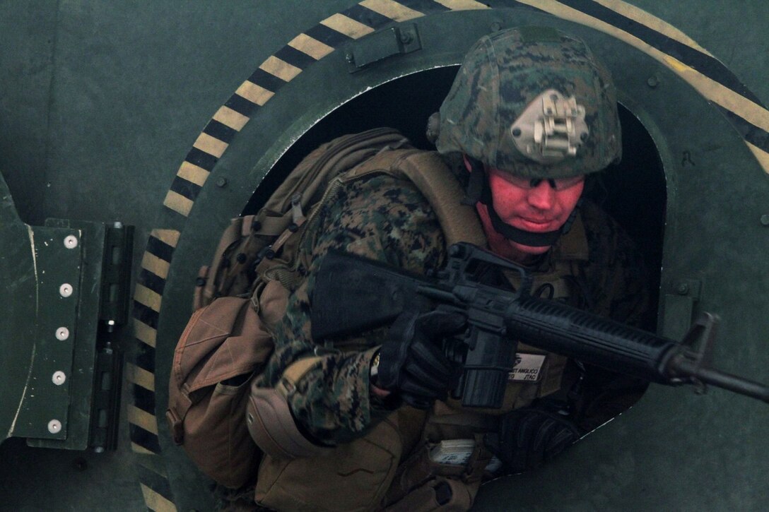 A Marine with 1st Air Naval Gunfire Liaison Company exits the humvee rollover simulator aboard Camp Pendleton, Calif., Nov. 20, 2013. In this round, the simulator stopped sideways and the Marines exited through the gunner hatch.