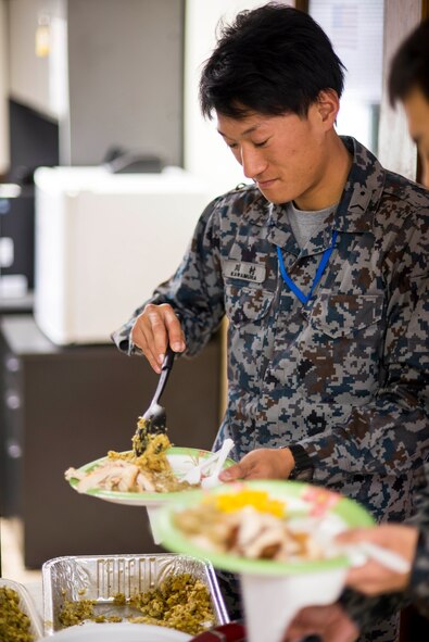 A member of the Japanese Air Self Defense Force receives food after bilateral training with the 18th Logistics Readiness Squadron fuels management flight on Kadena Air Base, Japan, Nov. 21, 2013. The Fuels Management Flight shared a Thanksgiving dinner with their JASDF counterparts, providing them with a taste of American culture.  (U.S. Air Force photo by Airman 1st Class Tyler Prince)