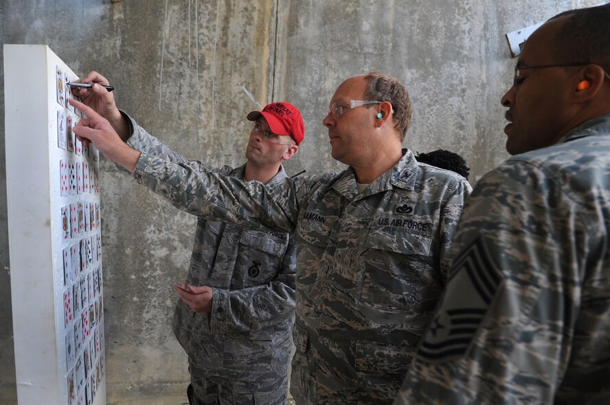 U.S. Air Force Staff Sgt. Jason Hershelman, 18th Security Forces Squadron combat arms instructor, reviews a target with Col. Jeffrey Ullmann, 18th Mission Support Group commander, and Chief Master Sgt. Rongi Langham, 18th Mission Support Group chief, during a "turkey shoot" on Kadena Air Base, Japan, Nov. 26, 2013. As part of the competition, team members had to work together to sight their targets to accurately hit five playing cards that each team had randomly selected. Each team was scored on the amount of playing cards they accurately hit. (U.S. Air Force photo by Senior Airman E. N. Jacobs)