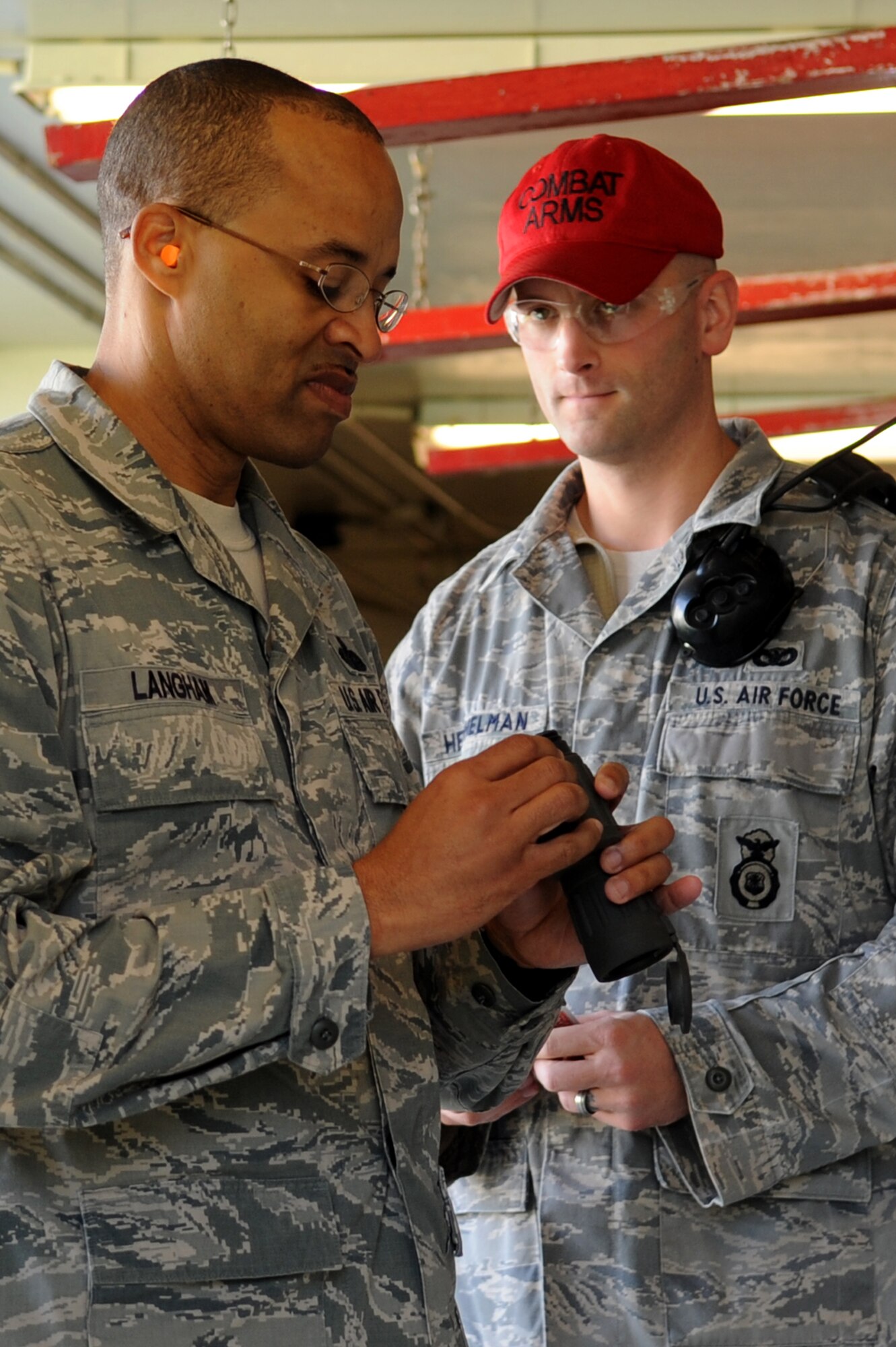 U.S. Air Force Chief Master Sgt. Rongi Langham, 18th Mission Support Group chief, reviews a handheld scope while Staff Sgt. Jason Hershelman, 18th Security Forces Squadron combat arms instructor, stands by ready to assist him during a "turkey shoot" on Kadena Air Base, Japan, Nov. 26, 2013. Rather than using a sighting scope on the M-4 rifle, each team had to rely on their teammate to help them accurately hit a target. (U.S. Air Force photo by Senior Airman E. N. Jacobs)