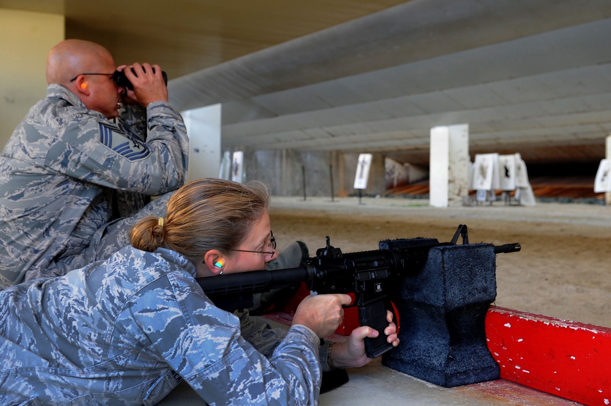 U.S. Air Force Col. Kathleen Weatherspoon, Force Support Squadron commander, fires an M-4 rifle while Chief Master Sgt. Hector Soler, 18th Security Forces Squadron chief, assists her during a "turkey shoot" on Kadena Air Base, Japan, Nov. 26, 2013. As part of the competition team members had to work together to sight their targets and accurately hit five playing cards that each team had randomly selected. Each team was scored on the amount of playing cards they accurately hit. (U.S. Air Force photo by Staff Sgt. Amber E. N. Jacobs)