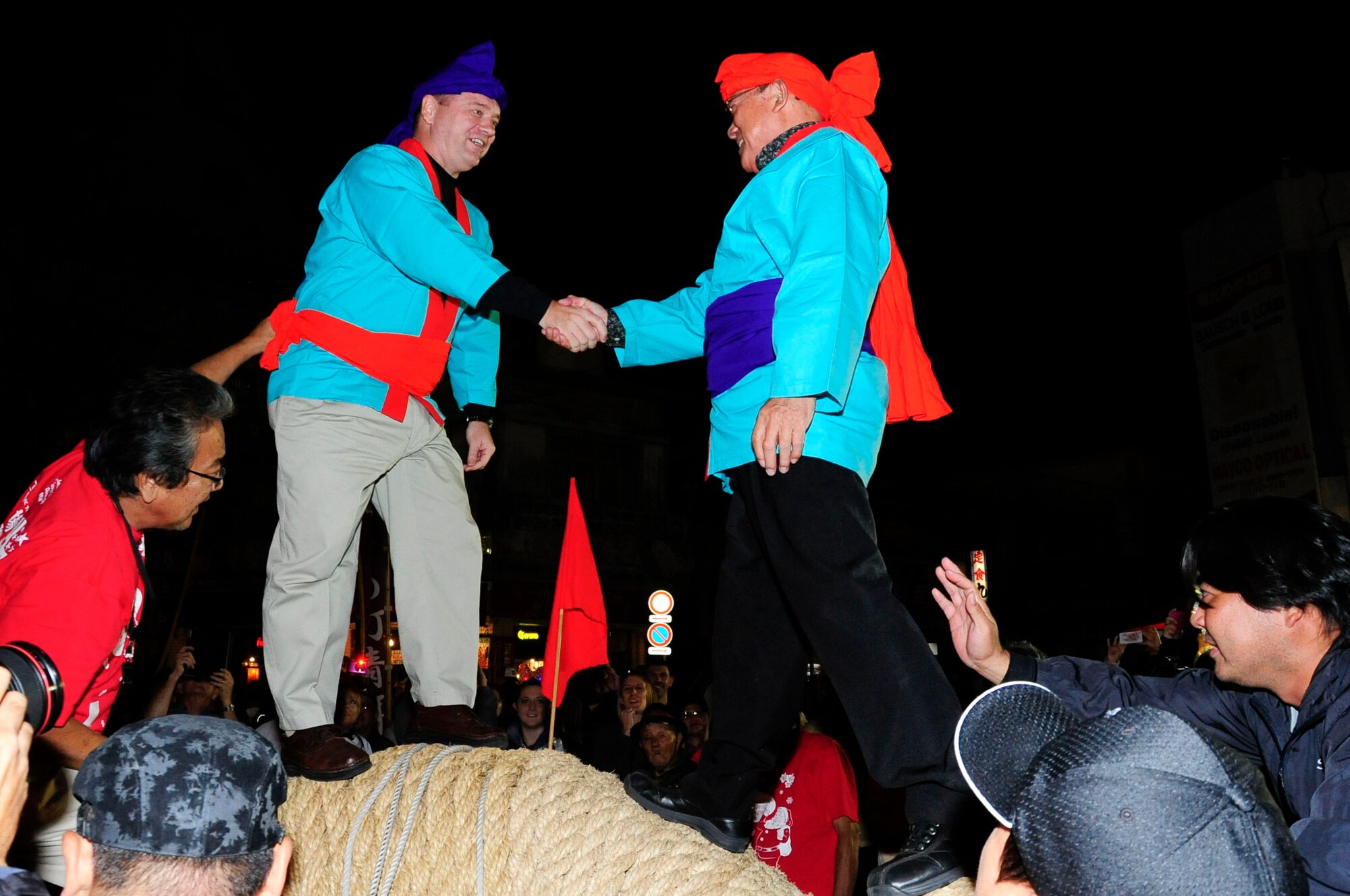 U.S. Air Force Col. Brian McDaniel, 18th Wing vice commander, shakes hands with Tomikichi Nakamura, Okinawa International Carnival Committee chairperson, before the tug-of-war match at the International Carnival in Okinawa City, Japan, Nov. 30, 2013. Both American and Okinawan participants, who formed teams, worked together to pull the giant rope in order to beat the other team during the giant tug-of-war. (U.S. Air Force photo by Staff Sgt. Darnell T. Cannady)