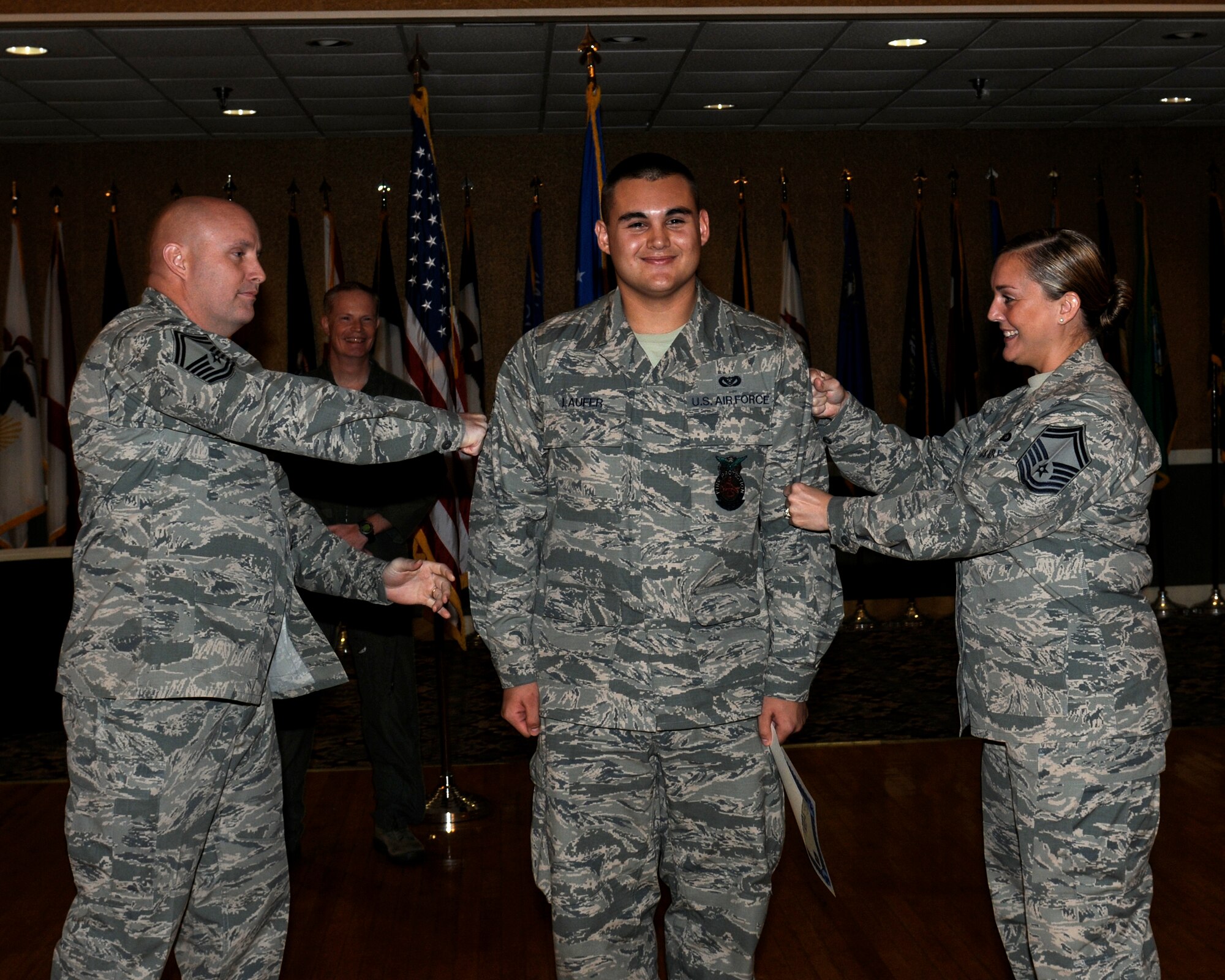 Senior Airman Jason Laufer, 14th Civil Engineer Squadron, has his third stripe tacked on by his parents, Senior Master Sgt. Robert N. Laufer, 2nd Bomb Wing Staff Superintendent, and Senior Master Sgt. Jennifer Laufer, Air Force Global Strike Command Chaplain Assistant MAJCOM Functional Manager at an Enlisted Promotions Ceremony Nov. 26 at the Columbus Club. Laufer said that the Air Force is a family tradition and that he is very proud to have his two parents, his mentors and counselors through the Air Force and through life, be at the promotion ceremony.
