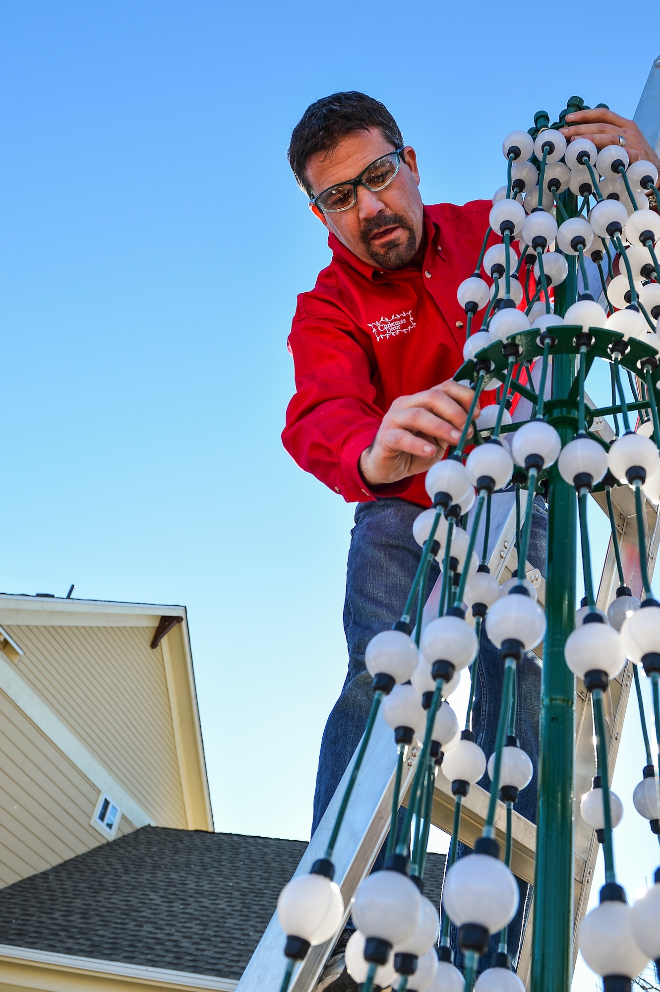 Blake Smith, Christmas Decor by Swingle Lawn, Tree & Landscape Care, assembles a lighted tree decoration Nov. 29, 2013, in family housing on Buckley Air Force Base, Colo. Maj. Matthew Anderson, 460th Civil Engineer Squadron, and his family applied and were selected for the Decorated Family Program which provided lights, wreaths other ornaments applied by a professional decorating team to military members and families. (U.S. Air Force photo by Senior Airman Riley Johnson/Released)