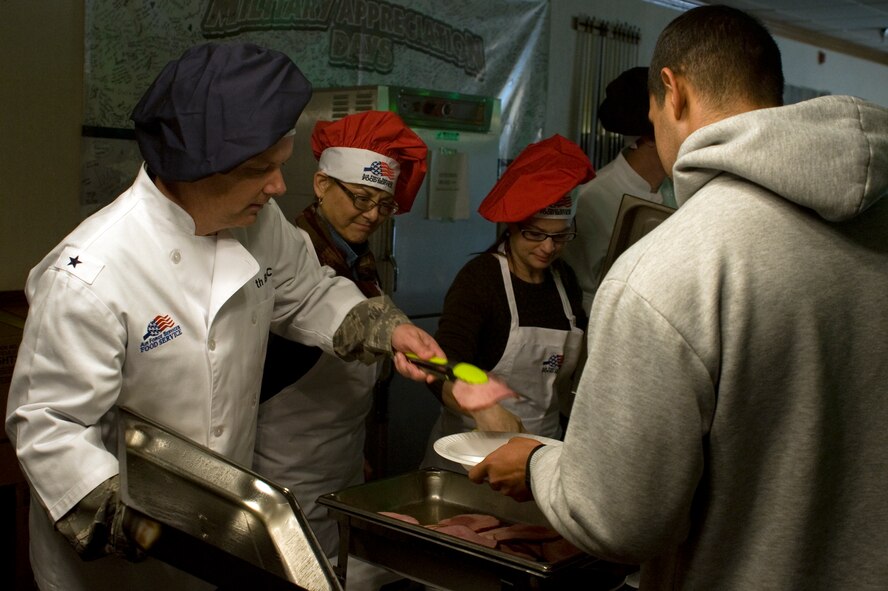 U.S. Air Force Brig. Gen. Glen VanHerck, 7th Bomb Wing Commander, and his wife, Marilyn, serve ham during Team Dyess’ annual Thanksgiving Day dinner Nov. 28, 2013, at Dyess Air Force Base, Texas. With the dining facility's ongoing transformation, 7th Force Support Squadron Airmen transported food from the kitchen in the facility to the Hangar Center Commons for Thanksgiving. Normally, these special event meals would be cancelled because of the building upgrades, however base leadership wanted to ensure the event took place. (U.S. Air Force photo by Senior Airman Peter Thompson/Released)