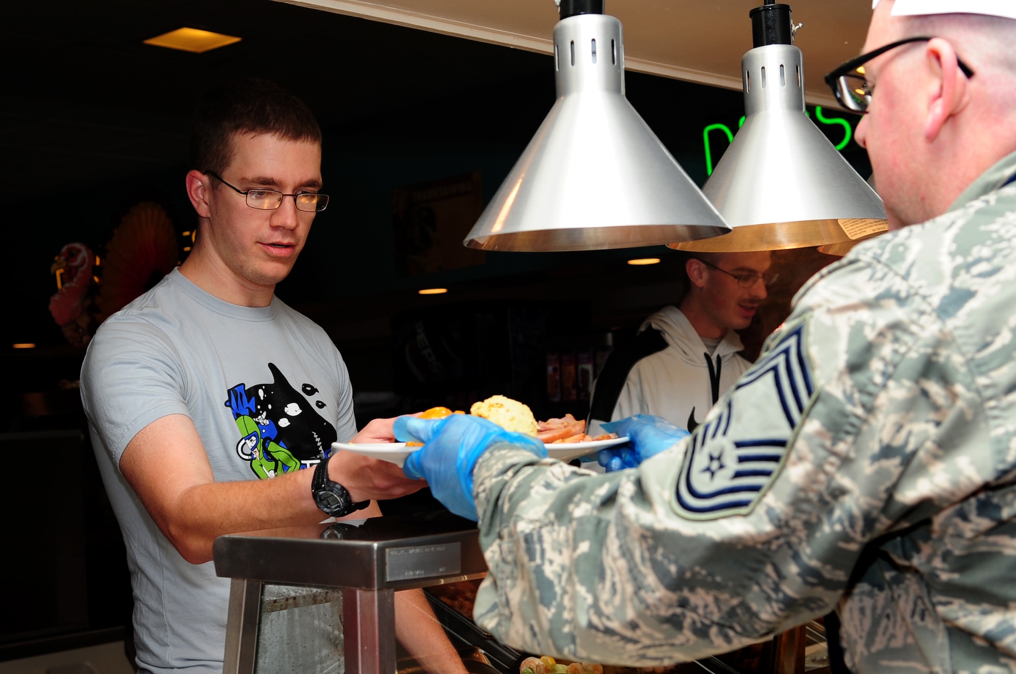 U.S. Air Force Airman 1st Class Dylan, 10th Intelligence Squadron system administrator, accepts a plate of food from Langley Air Force Base leaders during the Thanksgiving meal at the Crossbow Dining Facility at Langley Air Force Base, Va., Nov. 28, 2013.  Approximately 300 Service members, family members and retirees enjoyed the meal. (U.S. Air Force photo by Airman Areca T. Wilson/Released) (Last name withheld for security reasons.)
