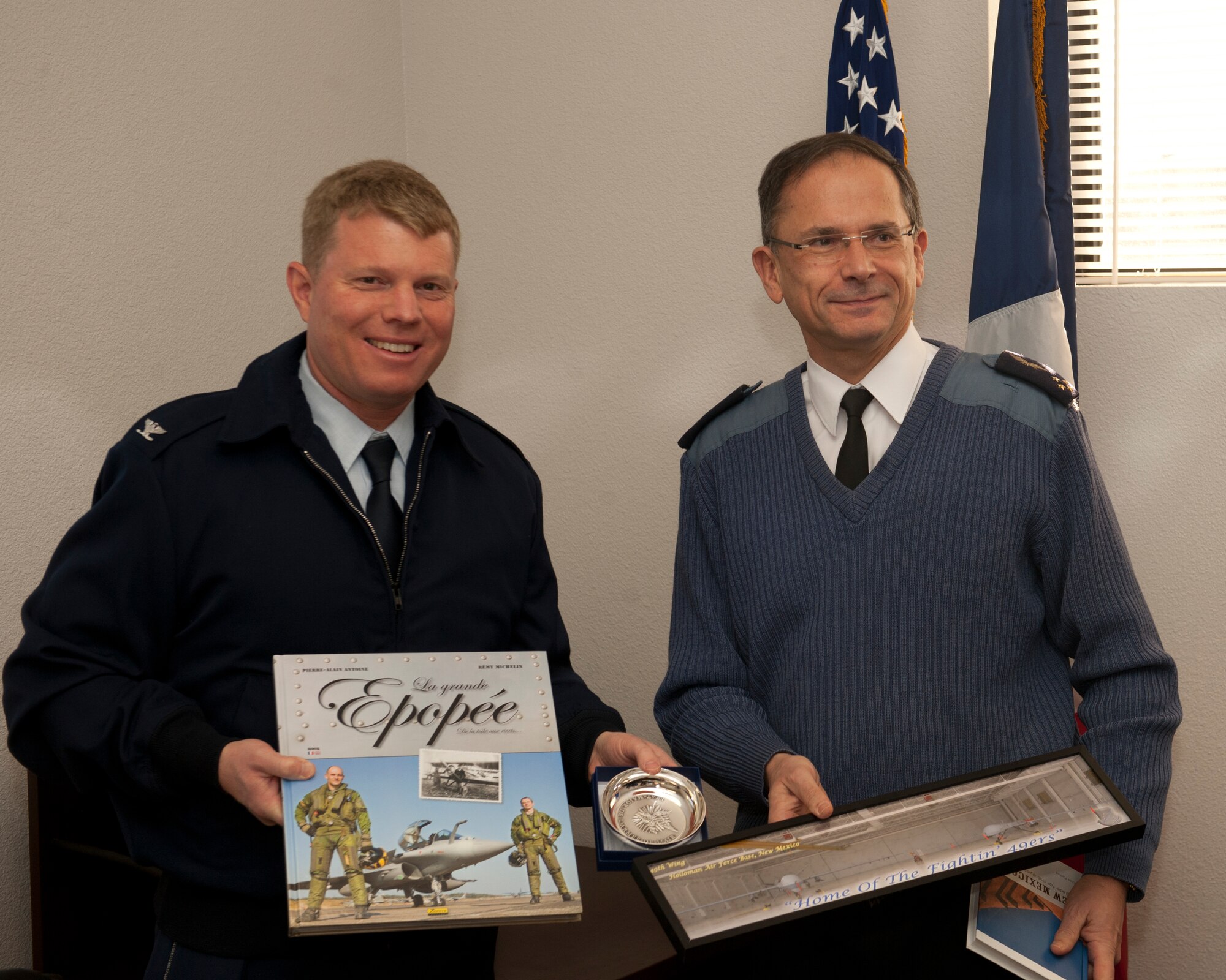 Colonel Andrew Croft, 49th Wing commander, exchanges gifts with Lt. Gen. Antoine Creux, French air force deputy chief of staff, at Holloman Air Force Base, N.M., Nov. 26. The French air force worked in collaboration with Holloman AFB to graduate six student pilots and sensor operators from the 16th Training Squadron.  The students became the first-ever French air force members to learn the MQ-9 Reaper system.  Their landmark graduation will mark the beginning of future coalition efforts between France and the United States to better utilize Remotely Piloted Aircraft across the world, Creux visited Holloman AFB both to take part in the graduation ceremony, and to tour Holloman AFB’s MQ-9 training facilities. (U.S. Air Force phot by Airman 1st Class Daniel E. Liddicoet/Released)


