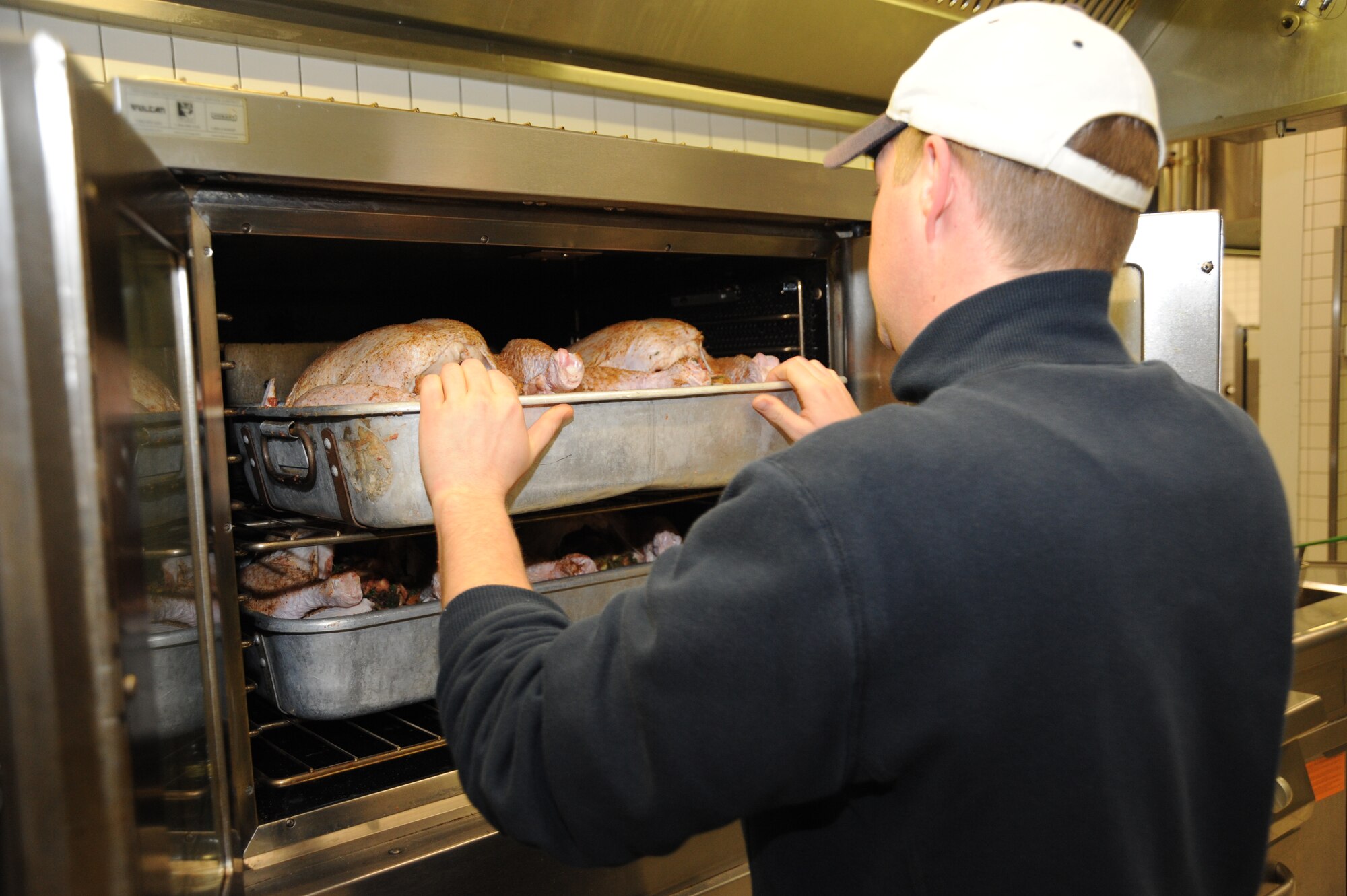SPANGDAHLEM AIR BASE, Germany-- Dennis Tautges, a chef for the 52nd Force Support Squadron, puts turkeys into an oven Nov. 28, 2013, at the Mosel Hall Dining Facility. Kitchen staff prepared 10 turkeys and eight hams for the Thanksgiving holiday meal. (U.S. Air Force photo by Airman 1st Class Dylan Nuckolls/Released)