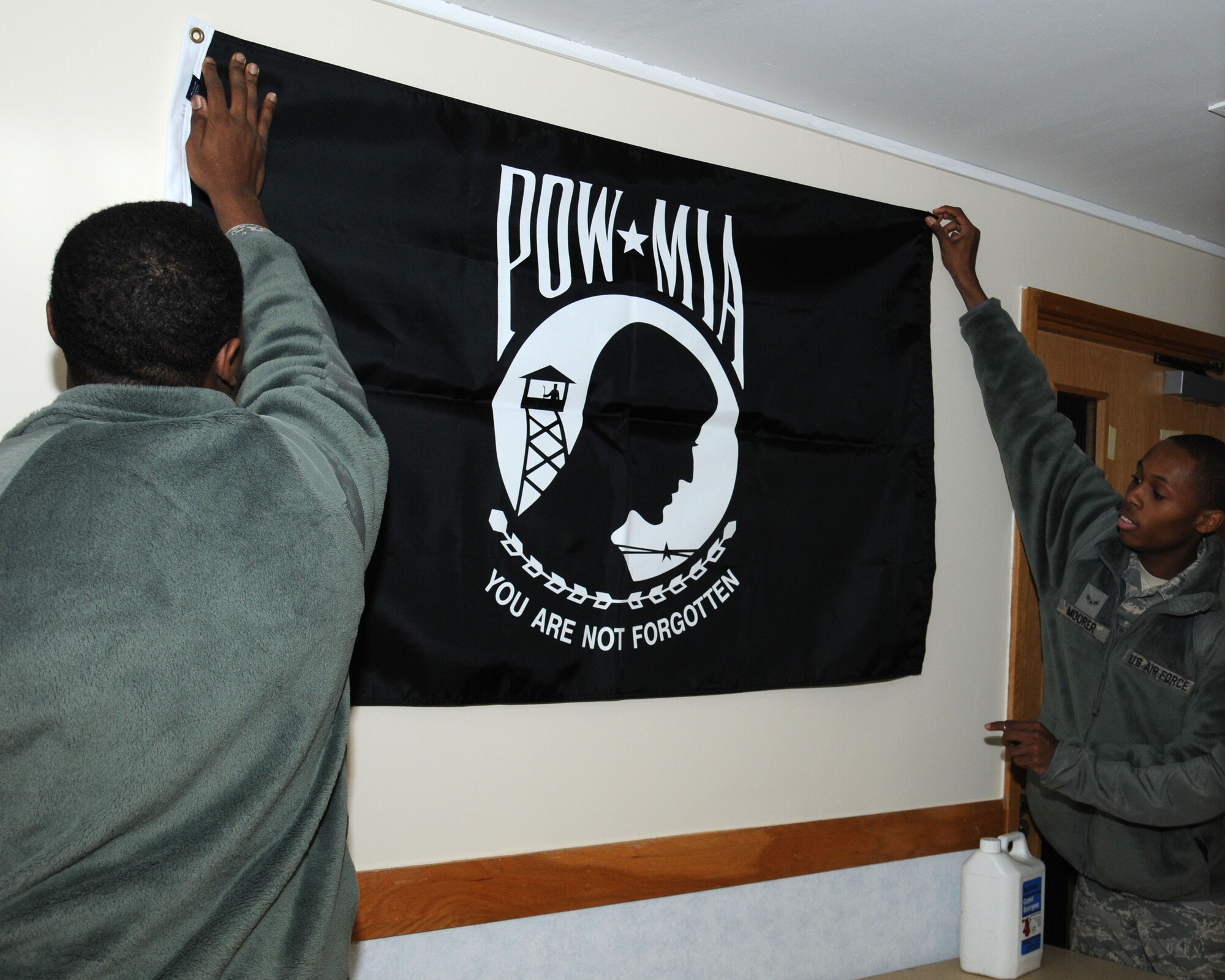 U.S. Air Force Airman 1st Class Tony Moorer, right, 100th Operations Support Squadron Aviation Resource Management apprentice from Detroit, and U.S. Air Force Airman 1st Class Johnarius Williams, 100th Aircraft Maintenance Squadron Aerospace Maintenance apprentice from Augusta, Ga., prepare space for a flag in the ground floor dayroom in dormitory 215 Nov. 26, 2013, on RAF Mildenhall, England. The furniture was moved to make a lounge for the Airmen Against Drunk Driving volunteers while on duty. Dormitory 215 is the next dormitory scheduled for renovation after dormitory 111’s completion. (U.S. Air Force photo by Gina Randall/Released)