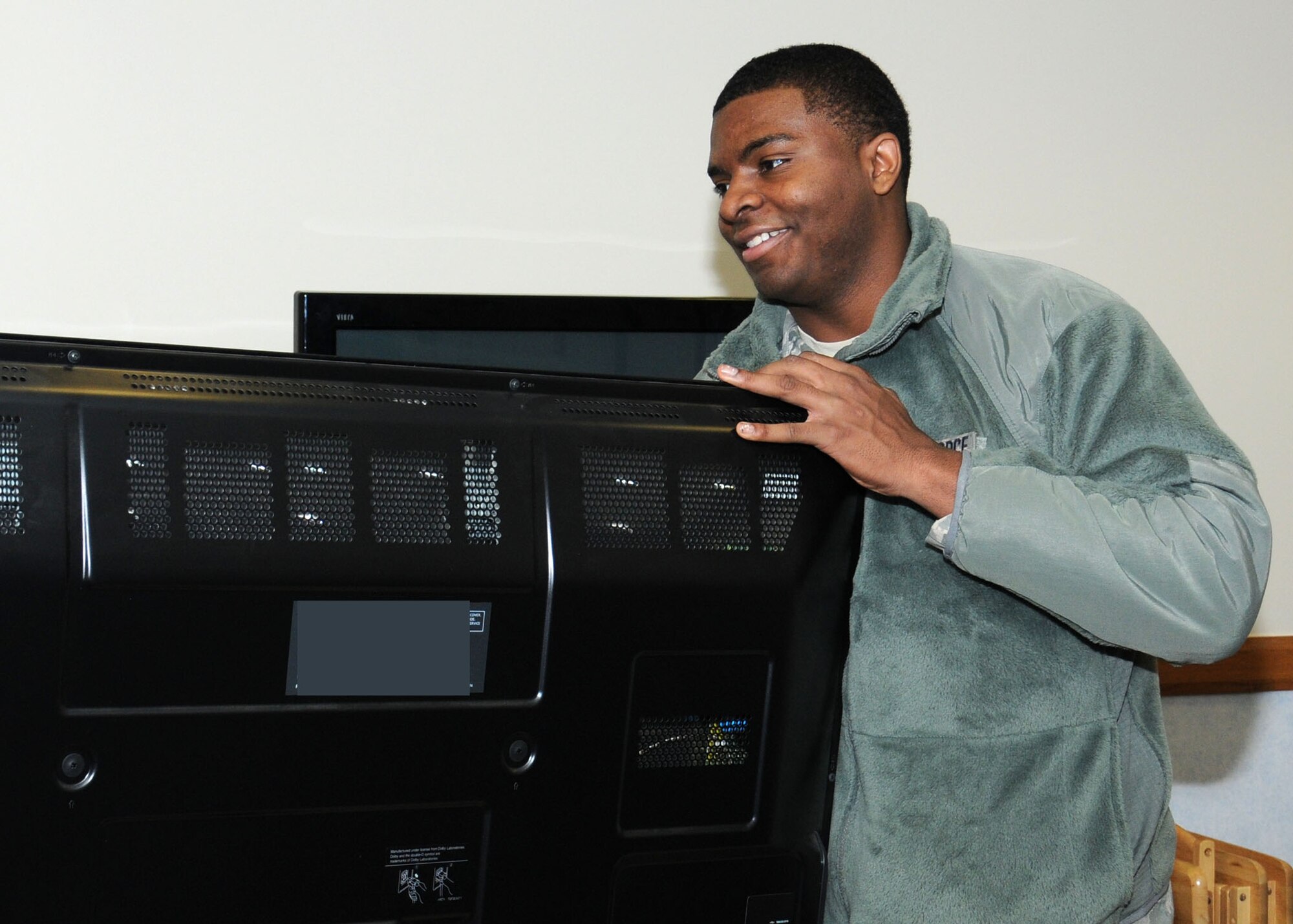 U.S. Air Force Airman 1st Class Johnarius Williams, 100th Aircraft Maintenance Squadron Aerospace Maintenance apprentice from Augusta, Ga., moves furniture and equipment from the base Chapel to dormitory 215 for the ground floor dayroom Nov. 26, 2013, on RAF Mildenhall, England. The furniture was moved to make a lounge for the Airmen Against Drunk Driving volunteers while on duty. The lounge provides entertainment and comfort for volunteers on shift. (U.S. Air Force photo by Gina Randall/Released)