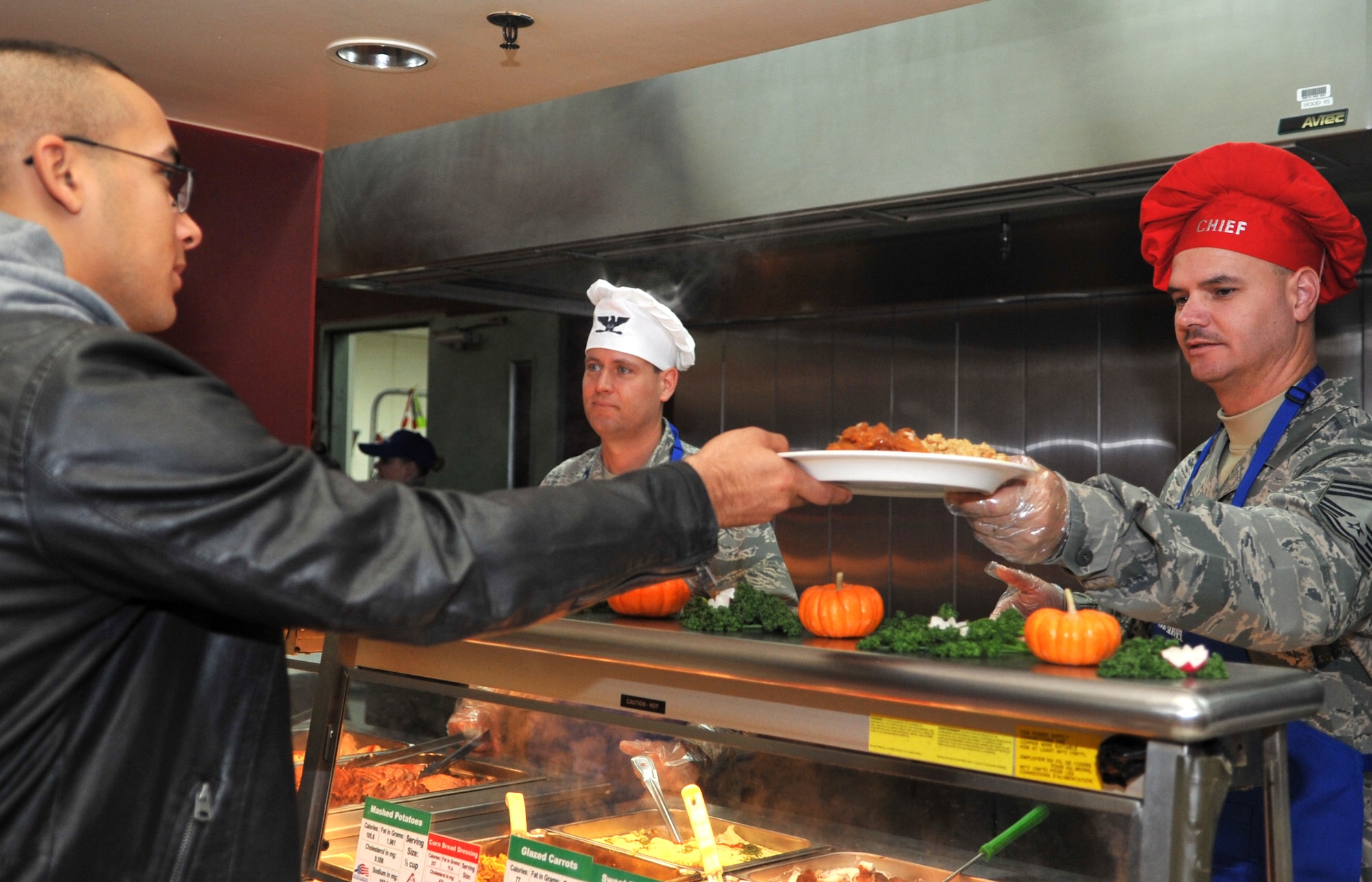 Chief Master Sgt. Derrick Grames, 51st Mission Support Group chief, hands a plate to an Airman in the Gingko Tree dining facility at Osan Air Base, Republic of Korea, Nov. 28, 2013. Osan’s dining facilities are normally only open to active duty service members, but during holiday meals retirees, civilian employees and family members are also welcome. (U.S. Air Force photo/Airman 1st Class Ashley J. Thum)
