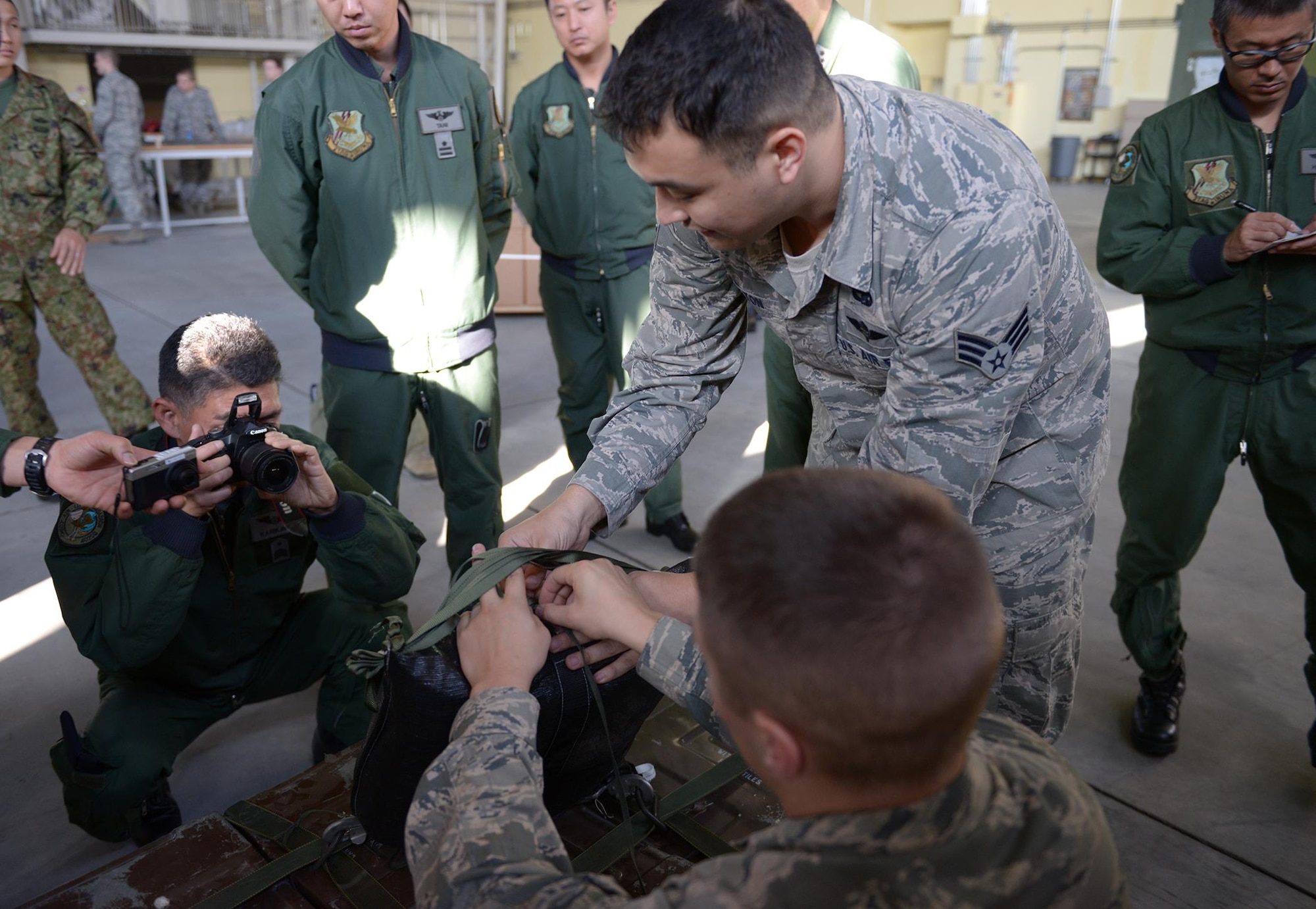 Senior Airmen Adam Caton and David Daniels display knots used for a low-cost, low-altitude pallet at Yokota Air Base, Japan, Nov. 26, 2013. The Airmen are air transportation specialists with the 374th Logistics Readiness Squadron. Members of Japan Air Self-Defense Force recorded images and details to expand their capabilities and use in the creation of their own low cost, low altitude process. 