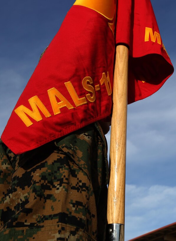 A Marine holds the Marine Aviation Logistics Squadron (MALS) 11 guidon during a cake-cutting ceremony aboard Marine Corps Air Station Miramar, Calif., Dec. 2. The Marines in the squadron celebrated its 92nd anniversary by sharing its history and cake.