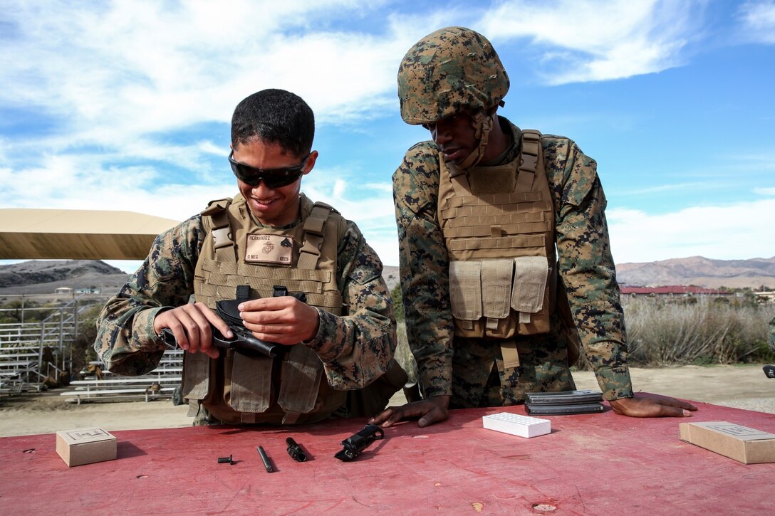 Corporal Richard Hernandez, left, data network specialist, 15th Marine Expeditionary Unit, helps Petty Officer 3rd Class Rylan Burchell, hospital corpsman, 15Tth MEU, assemble his issued M9 pistol during a small-arms training exercise at Range 111 aboard Camp Pendleton, Calif., Nov. 25. The training focused on enhancing the unit’s confidence and proficiency with personal weapons and M67 Fragmentation Hand Grenades. Hernandez, 22, is from Temecula, Calif. Burchell, 25, is from Brooklyn, N.Y. (U.S. Marine Corps photo by Cpl. Emmanuel Ramos)