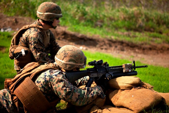 Lance Cpl. Joshua White, a rifleman with 1st Battalion, 3rd Marine Regiment coaches as a personnel safety officer while a Marine shoots an M203 40 mm grenade launcher during new equipment testing for a recently developed sight at Kaneohe Bay range training facility Nov. 19. Marine Corps Systems Command coordinated the training and is fielding the new sight. 
