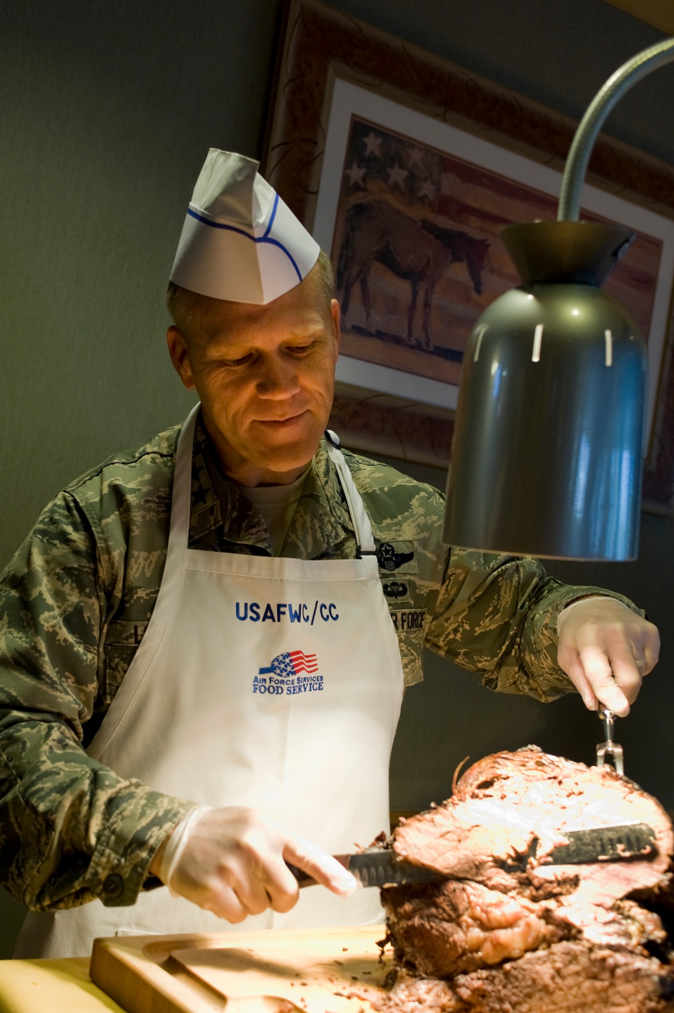 U.S. Air Force Maj. Gen. Jeffrey Lofgren, U.S. Air Force Warfare Center commander, cuts roast beef during the Thanksgiving meal at the Crosswinds Dining Facility Nov. 28, 2013, at Nellis Air Force Base, Nev. Each year senior leadership and their families serve a Thanksgiving meal to active duty military, retirees and their dependants. (U.S. Air Force photo by Senior Airman Matthew Lancaster)