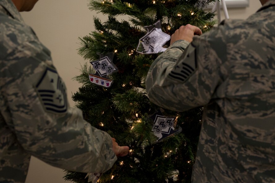Members from Team Holloman’s First Sergeants’ Council hang Diamond Tree ornaments in the Holloman Base Exchange Nov. 26, 2013.  The annual Diamond Tree program offers support to Holloman military families that need assistance in providing Christmas gifts for their children.(U.S. Air Force photo by Airman 1st Class Chase Cannon/Released)