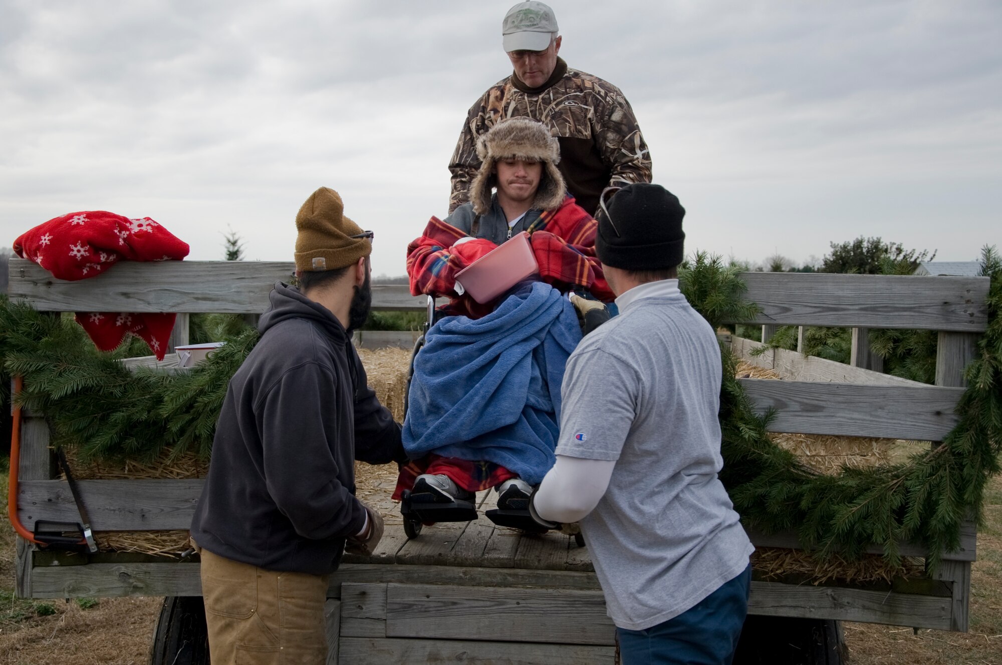Alberto Soto, 512th Civil Engineer Squadron firefighter and wounded warrior, is lowered after a hayride by three Evergreen Farms employees Nov. 30, 2013, at Evergreen Farms in Dover, Del. The farm donated 16 trees to wounded warriors and families in need. (U.S. Air Force photo/Senior Airman Jared Duhon)