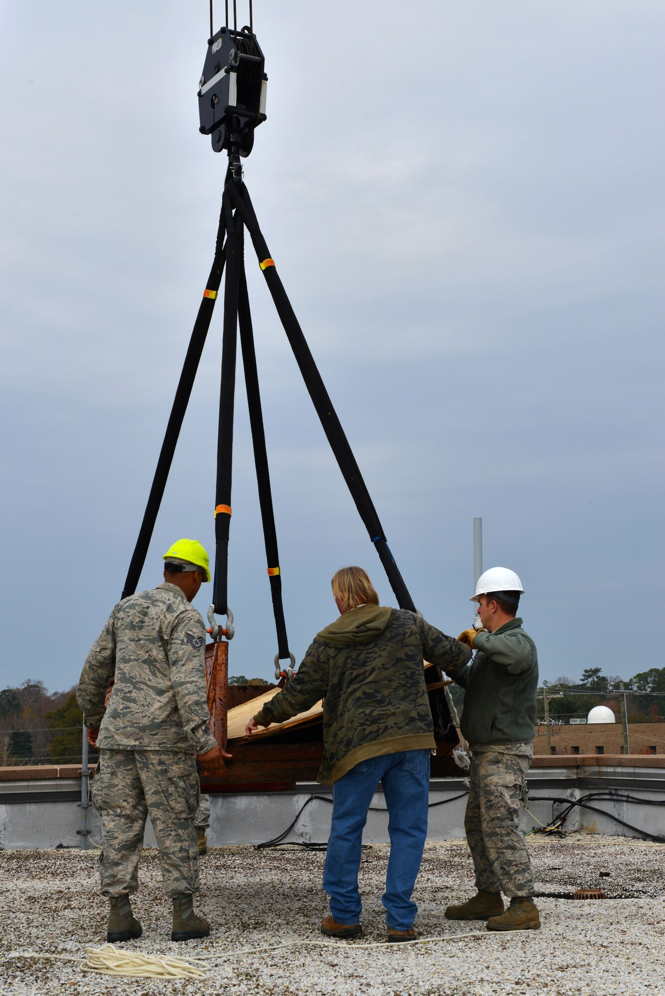 U.S. Air Force Airmen from the 20th Civil Engineering Squadron position a crane lifted container on the roof of the 20th Fighter Wing Headquarters building at Shaw Air Force Base S.C., Dec. 3, 2013.  The Airmen and civilian contractors were replacing old skylight windows that had been leaking water with new windows. (U.S. Air Force photo by Airman 1st Class Jensen Stidham/Released)