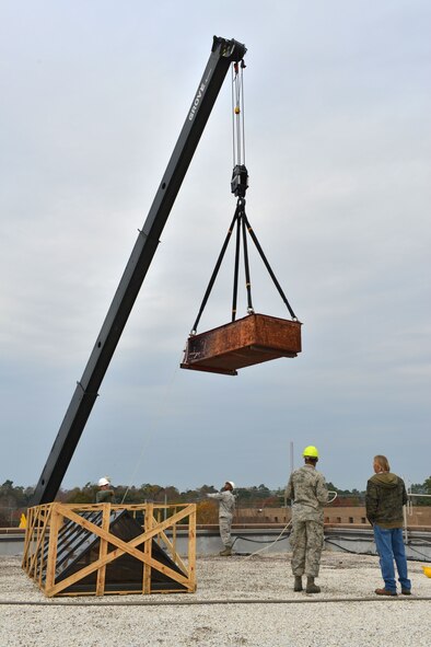U.S. Air Force Airmen from the 20th Civil Engineering Squadron await a crane lifted container on the roof of the 20th Fighter Wing Headquarters building at Shaw Air Force Base S.C., Dec. 3, 2013.  The Airmen and civilian contractors were replacing old skylight windows that had been leaking water. (U.S. Air Force photo by Airman 1st Class Jensen Stidham/Released)