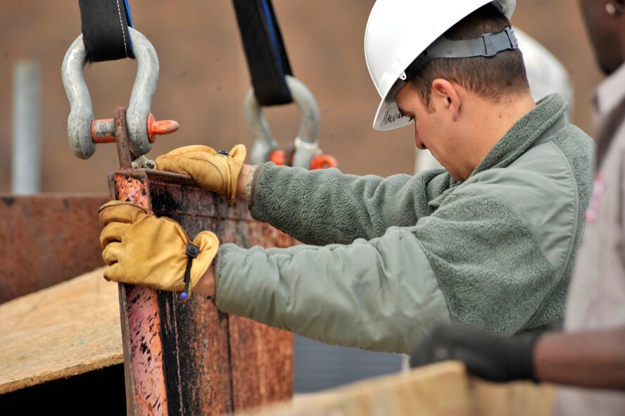 U.S. Air Force Staff Sgt. Ricky Gennie, 20th Civil Engineering Squadron structures journeyman, directs a metal container onto a roof at Shaw Air Force Base S.C., Dec. 3, 2013. Gennie along with several other Airmen and civilian contractors crane lifted new skylight windows onto the roof of the 20th Fighter Wing Headquarters building to replace old windows. (U.S. Air Force photo by Airman 1st Class Jensen Stidham/Released)