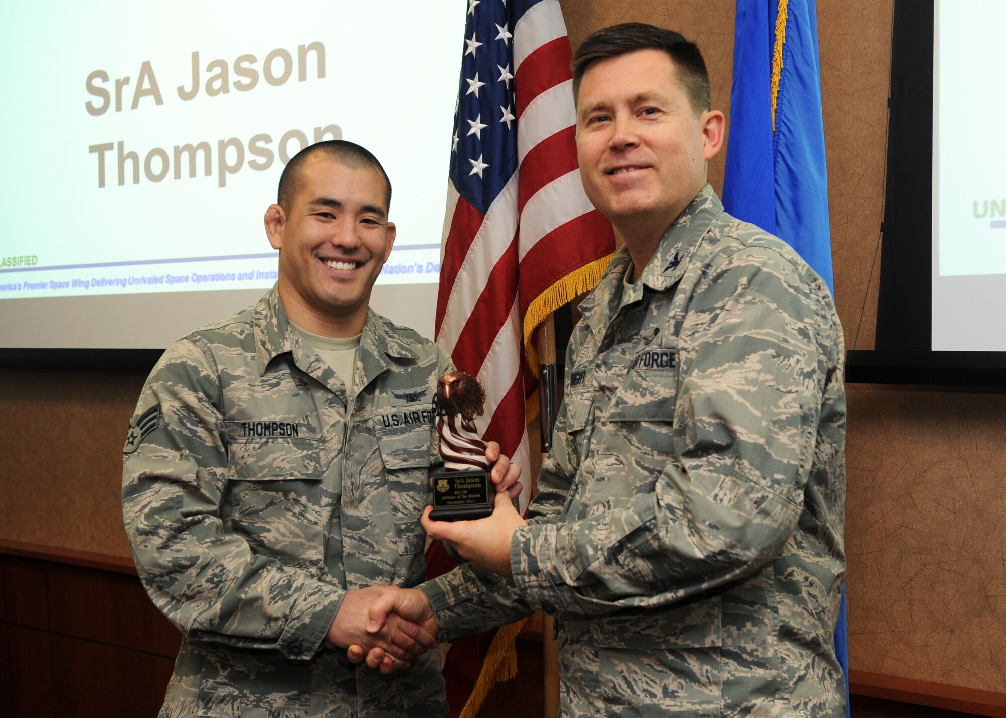Senior Airman Jason Thompson, 460th Operations Group data systems operator, receives the 460th Space Wing Airman of the Month Award for November from Col. Dan Wright, 460th SW commander, Dec. 3, 2013, at Buckley Air Force Base, Colo. Thompson received the award for his exceptional service in executing the space wing’s first Management Internal Control Toolset deficiency capability, building five checklists for 34 errors. Thompson also inspected 25 individual qualification folders identifying one critical systemic fault and averting a critical readiness crisis which was key to the groups Air Force Inspection System. (U.S. Air Force photo by Senior Airman Marcy Copeland/Released)