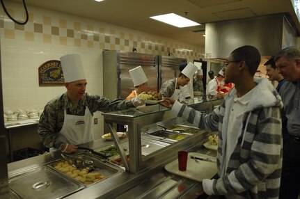 Chief Master Sgt. Shawn Hughes, 437th Airlift Wing command chief, serves an Airman Thanksgiving dinner Nov. 28, at the Gaylor Dining Facility at Joint Base Charleston - Air Base, S.C. Base leadership from the 628th Air Base Wing, 437th AW and 315th AW, along with their families, served the Thanksgiving feast to retirees, Airmen and their families. (U.S. Air Force photo/ Staff Sgt. William O'Brien)