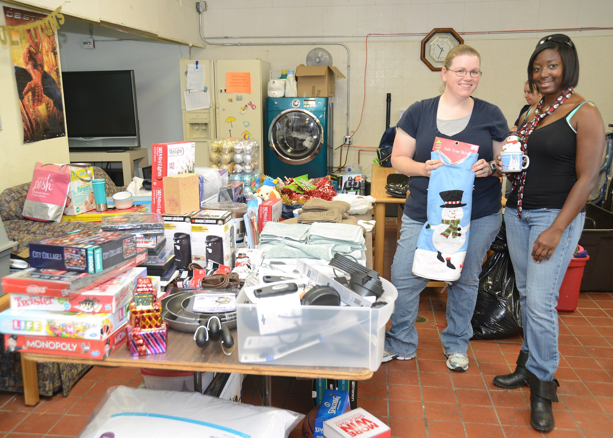 Calla Hines (left) and Japhia Logan, Airman's Attic lead volunteers, show off items donated by the Lancaster, Calif., Rotary Club Dec. 3. The Lancaster chapter purchased $1,600 worth of items to help out young Airmen who can come to the Airman's Attic and pick up items free of charge. (U.S. Air Force photo by Kenji Thuloweit)