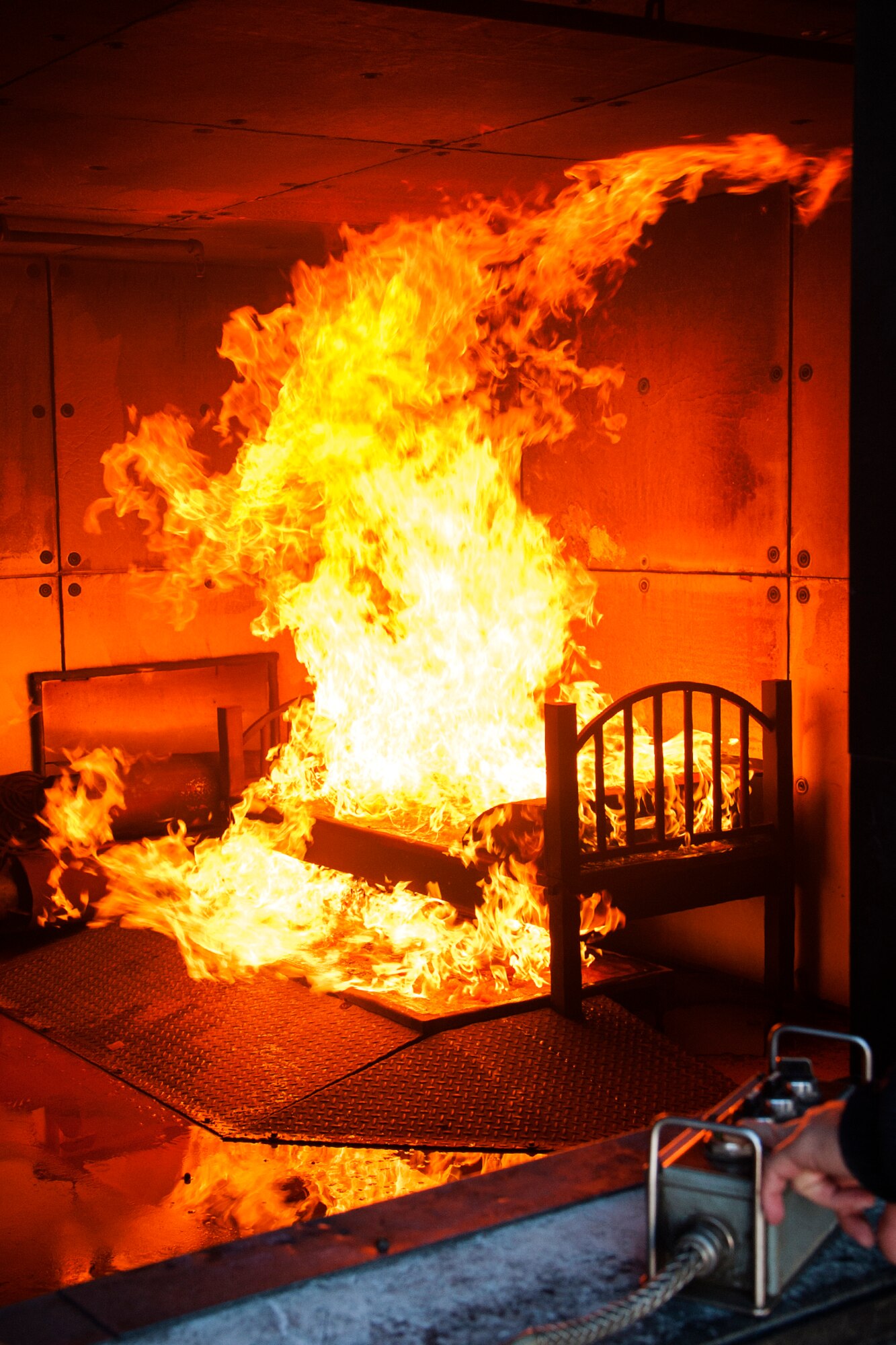 PETERSON AIR FORCE BASE, Colo. -- A fire rages in a mock bedroom at the 21st Civil Engineer Squadron fire department structural training facility. Fire fighters used this training fire to practice different techniques and spray patterns, and are able to see first-hand how it affects a fire. The two-floor facility is also used for training on barbecue and kitchen fires, as well as practicing roof cut-aways and rappelling. (U.S. Air Force photo/Craig Denton)