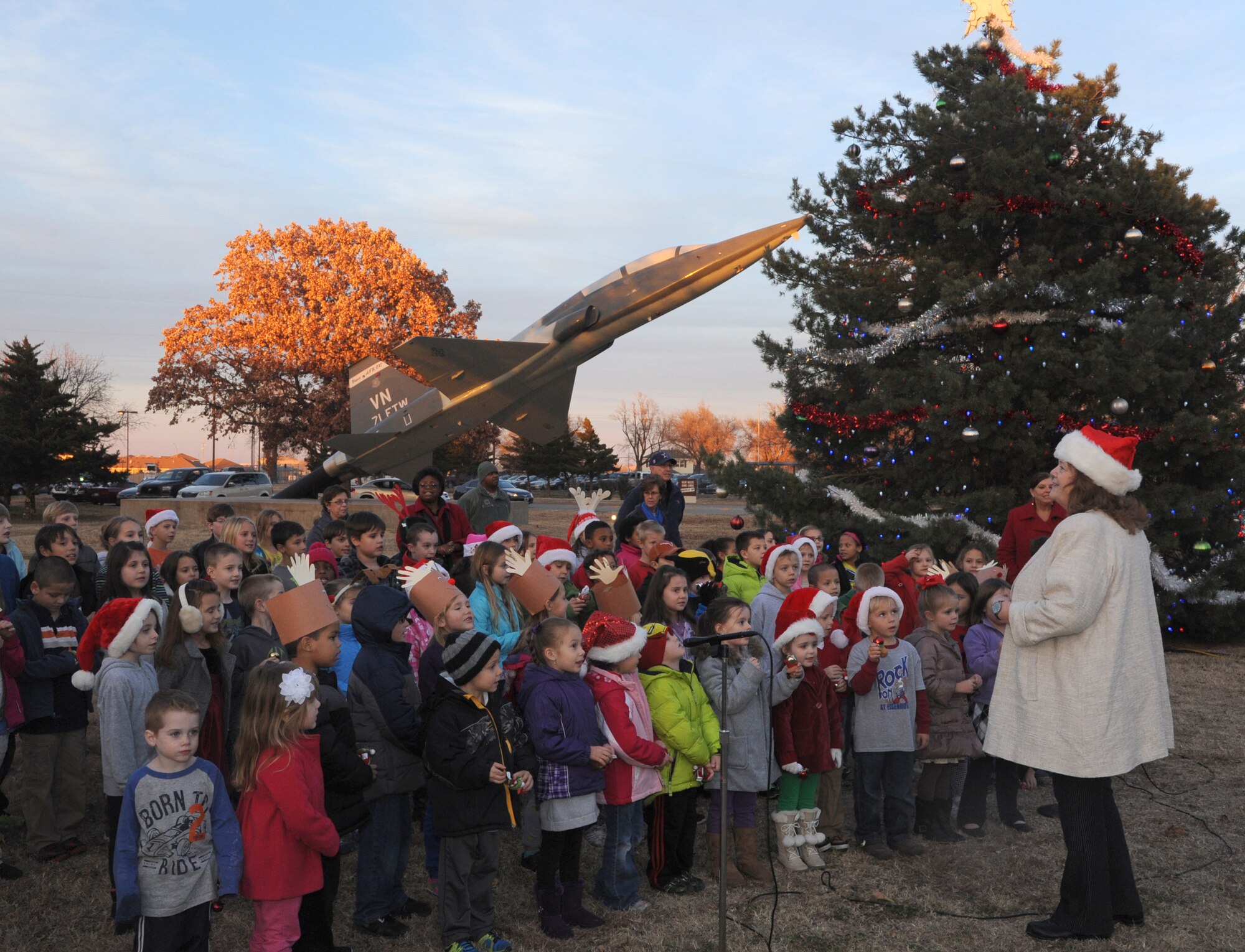 Nancy Dillard, in white coat, leads the Eisenhower Elementary School choir in traditional holiday songs at the Vance Air Force Base Christmas Tree lighting ceremony Dec. 2. (U.S. Air Force photo/ Senior Airman Frank Casciotta)