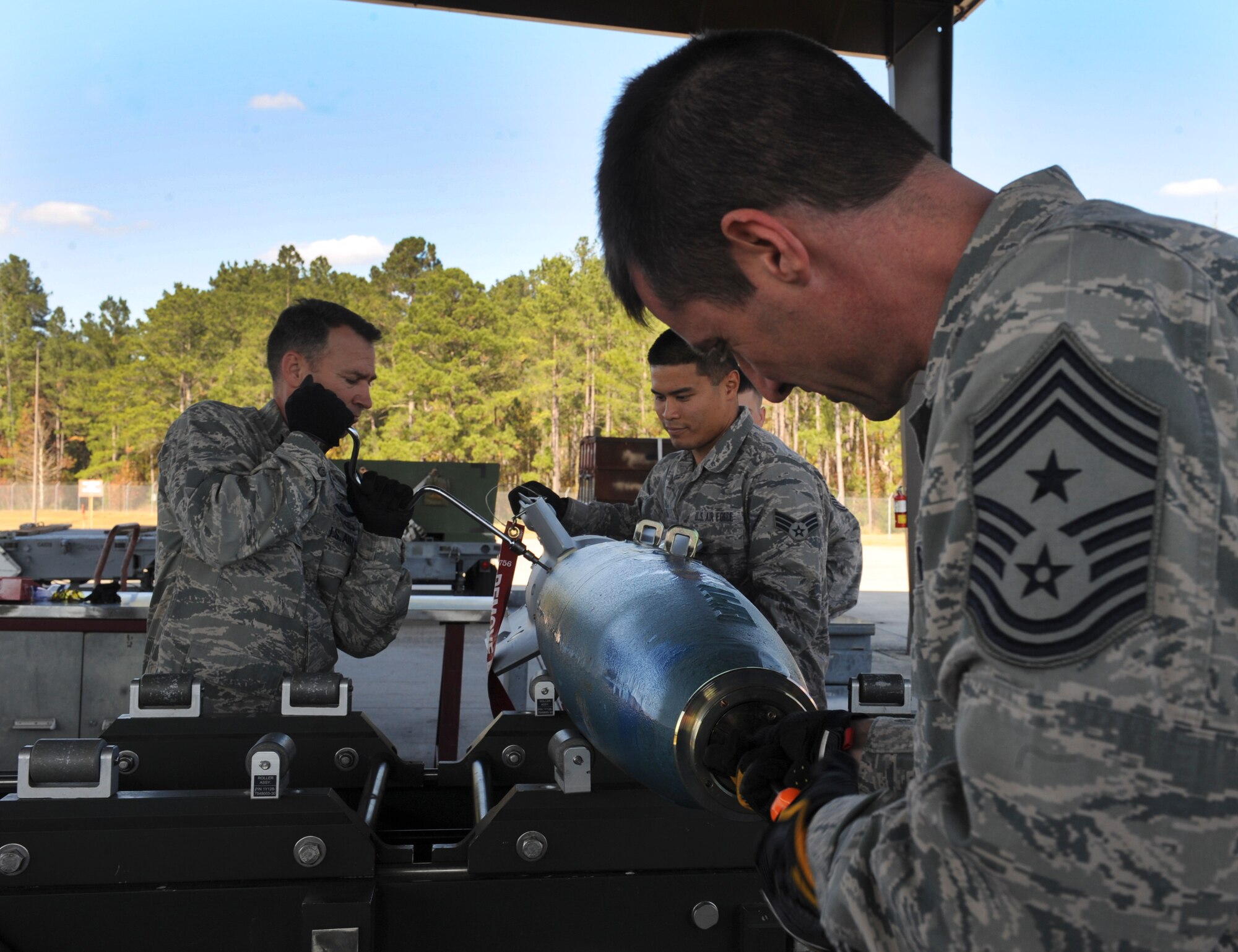 U.S. Air Force Chief Master Sgt. Matthew Wells, 23d Wing command chief, attaches the forward adapter while Col. Chad Franks, 23d WG commander, tightens the fin assembly on a practice GBU-12 laser-guided bomb at Moody Air Force Base, Ga., Dec. 2, 2013. After completing the building process, the bomb is marked with a tracking number and delivered to the weapons load crew. (U.S. Air Force photo by Senior Airman Olivia Bumpers/Released) 