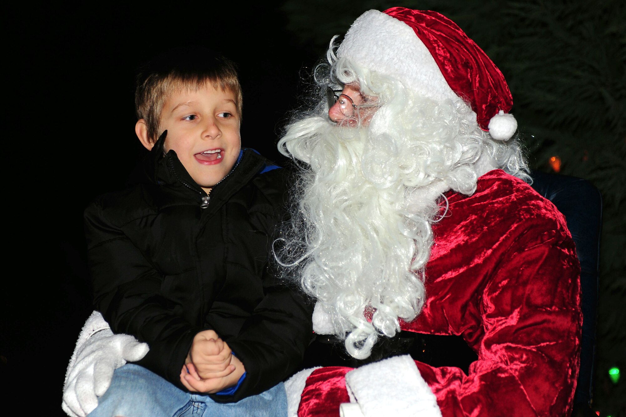 A child sits with Santa Claus during the holiday tree lighting ceremony at Seymour Johnson Air Force Base, N.C., Dec. 2, 2013. Santa assisted with the holiday tree lighting and spoke with children about their holiday wishes. (U.S. Air Force photo by Airman 1st Class John Nieves Camacho)