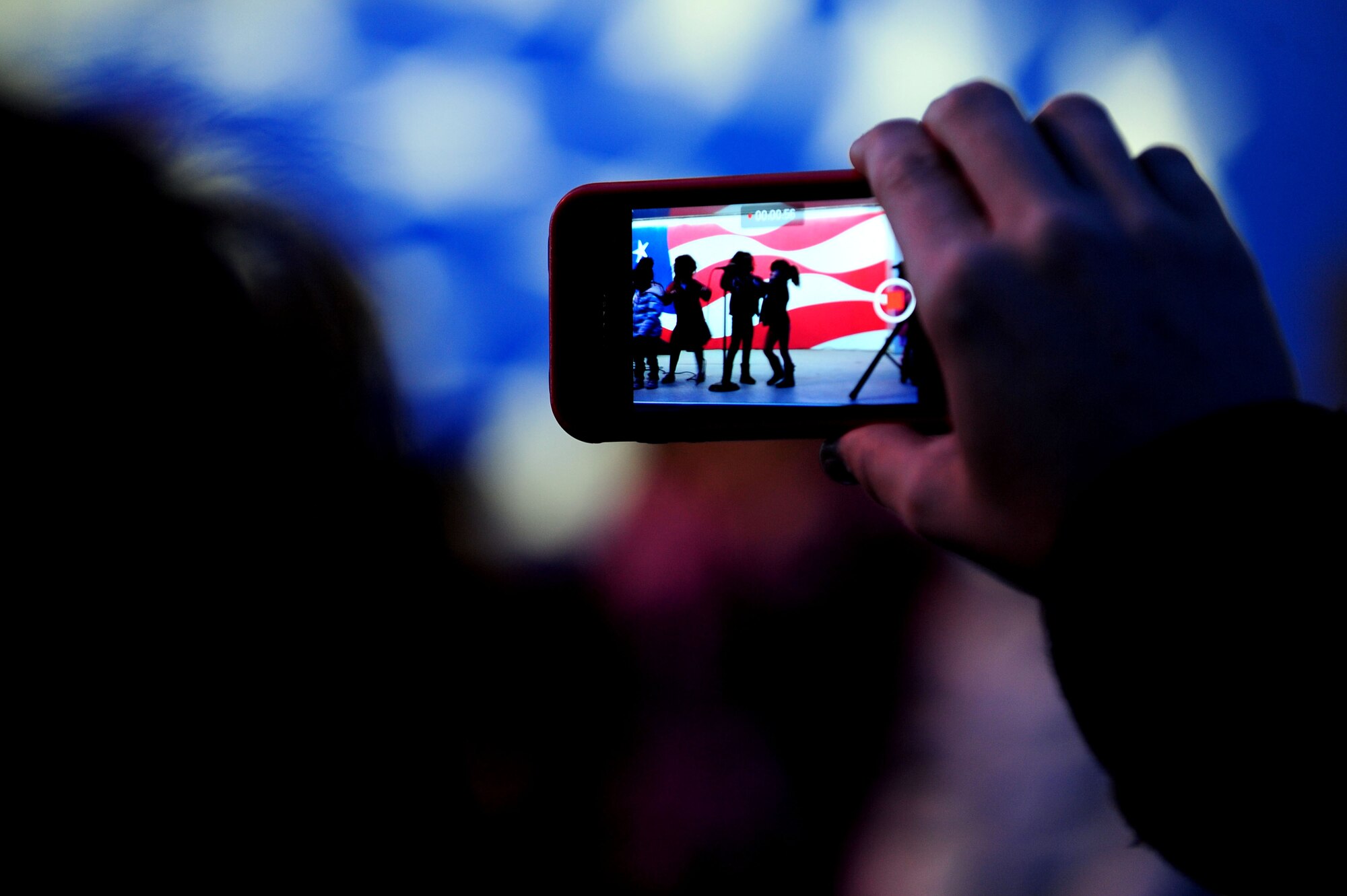 A patron at the holiday tree lighting ceremony records children from the Youth Center performing at Seymour Johnson Air Force Base, N.C., Dec. 2, 2013. Three different age groups sang holiday carols during the ceremony. (U.S. Air Force photo by Airman 1st Class John Nieves Camacho)