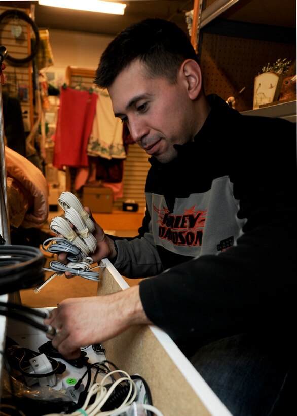 Senior Airman Jesus Ortiz, 28th Aircraft Maintenance Squadron support flight technician, cleans out and organizes electric cords in the B-ONE Yard Thrift and Consignment store at Ellsworth Air Force Base, S.D., Nov. 23, 2013. The class of more than 27 Airmen completed on several projects at the facility throughout the day including repainting walls, organizing and labeling inventory and giving the building a good scrubbing. (U.S. Air Force photo by Senior Airman Anania Tekurio/Released)