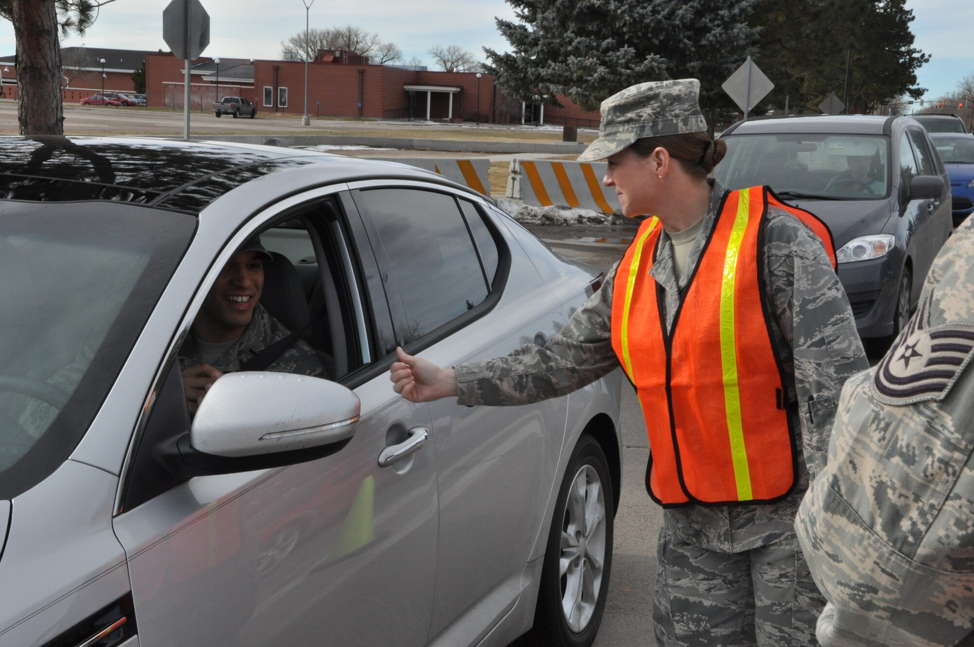 131127-F-GP871-018 Col. Tracey Hayes, 90th Missile Wing commander, passes out lollipops at the front Nov. 27 while wishing Airmen leaving base a happy and safe Thanksgiving and holiday weekend. Hayes and Chief Master Sgt. Mike Garrou, 90th MW command chief, volunteered their time to stress the importance of having a plan during the four-day weekend. (U.S. Air Force photo by Tech. Sgt. Stacy Foster)