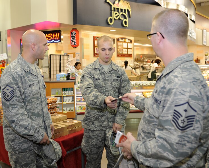 Master Sgts. David Bedner, left, 2nd Civil Engineer Squadron first sergeant, and Chad Kraus 2nd Operations Group first sergeant, surprise Senior Airman Charles Turner, 2nd Maintenance Squadron, with a gift card at the Commissary on Barksdale Air Force Base, La., Nov. 7, 2013. First sergeants surprised Airmen and their families with gift cards to help them during the holidays, as part of a Random Act of Kindness event. (U.S. Air Force photo/Senior Airman Joseph A. Pagán Jr.)