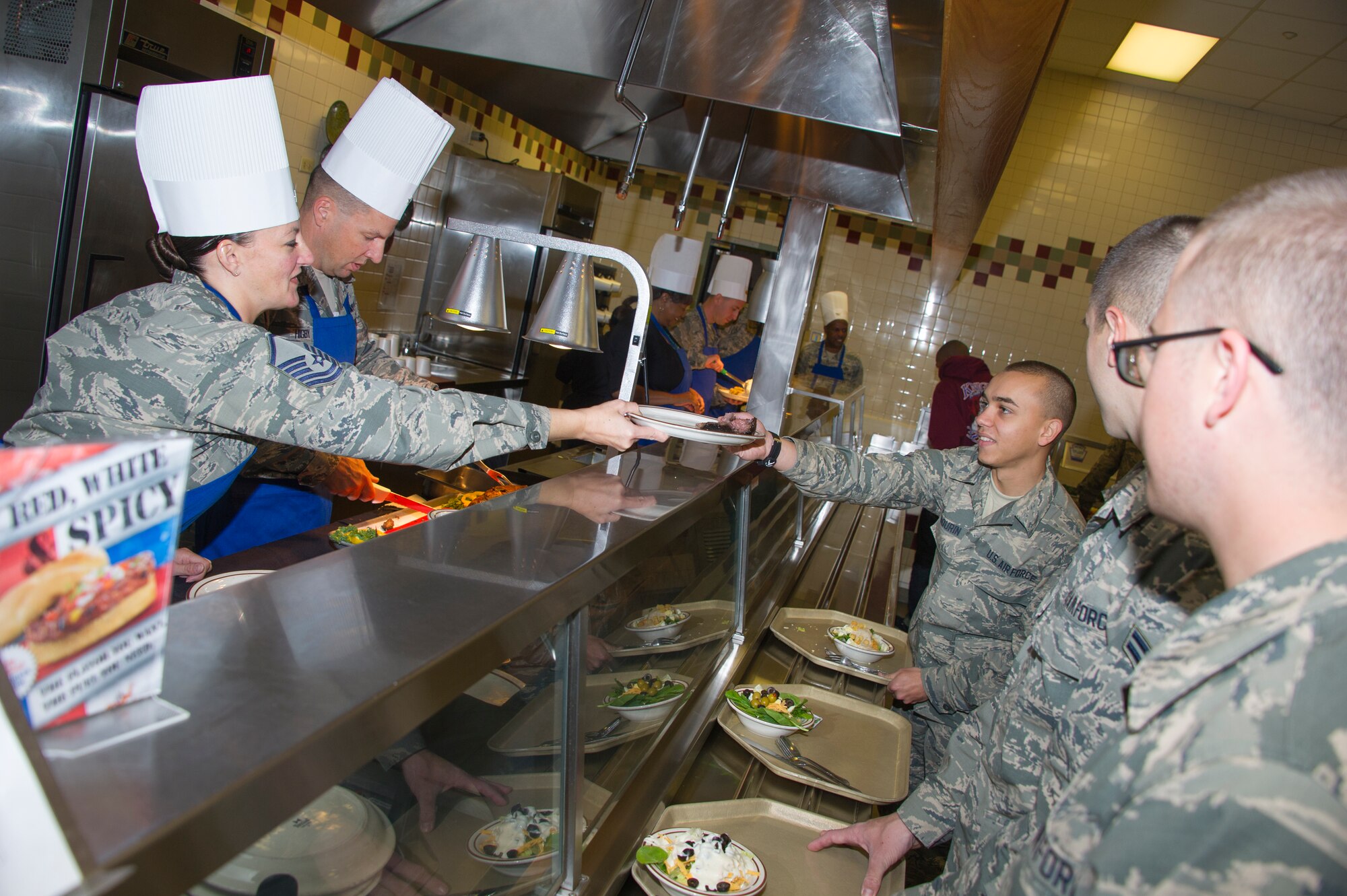 Master Sgt. Laurie Holmes, 334th Training Squadron, passes a plate of roast beef to  Airman 1st Class Matthew Sabourin, 338th Training Squadron, as Brig. Gen. Patrick Higby, 81st Training Wing commander, slices roast beef for serving during Thanksgiving lunch Nov. 28, 2013, at the Azalea Dining Facility, Keesler Air Force Base, Miss.  Wing leadership continued a Keesler annual tradition by serving food to Airmen for the holiday. (U.S. Air Force photo by Adam Bond)