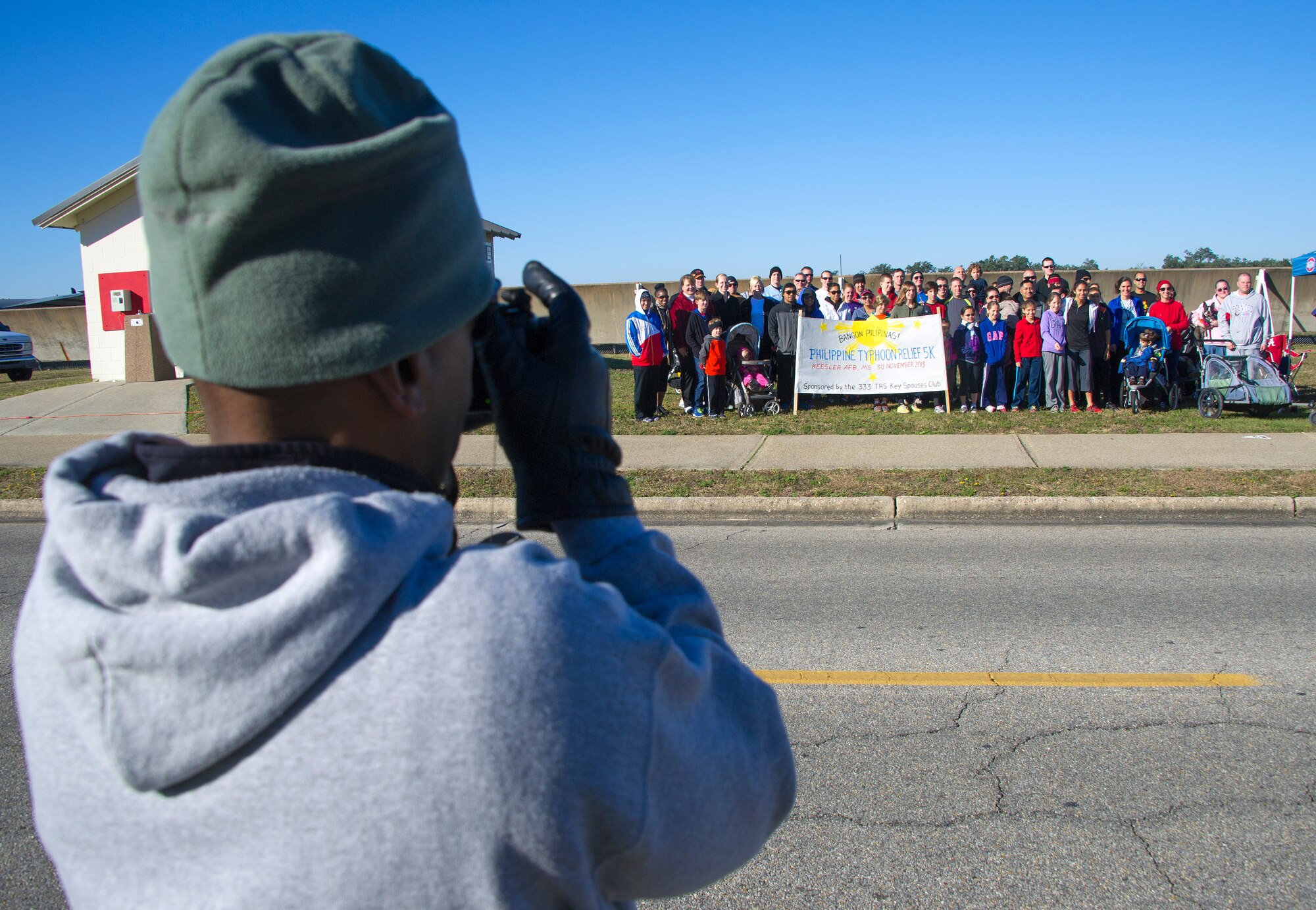 Lt. Col. Whitney McCloud, 333rd Training Squadron commander, takes a group photo of the 53 individuals that participated in a 5km run Nov. 30, 2013, at Keesler Air Force Base, Miss.  The event, sponsored by the 333rd Training Squadron key spouses, was in support of the Philippine typhoon relief effort.  (U.S. Air Force photo by Adam Bond)
