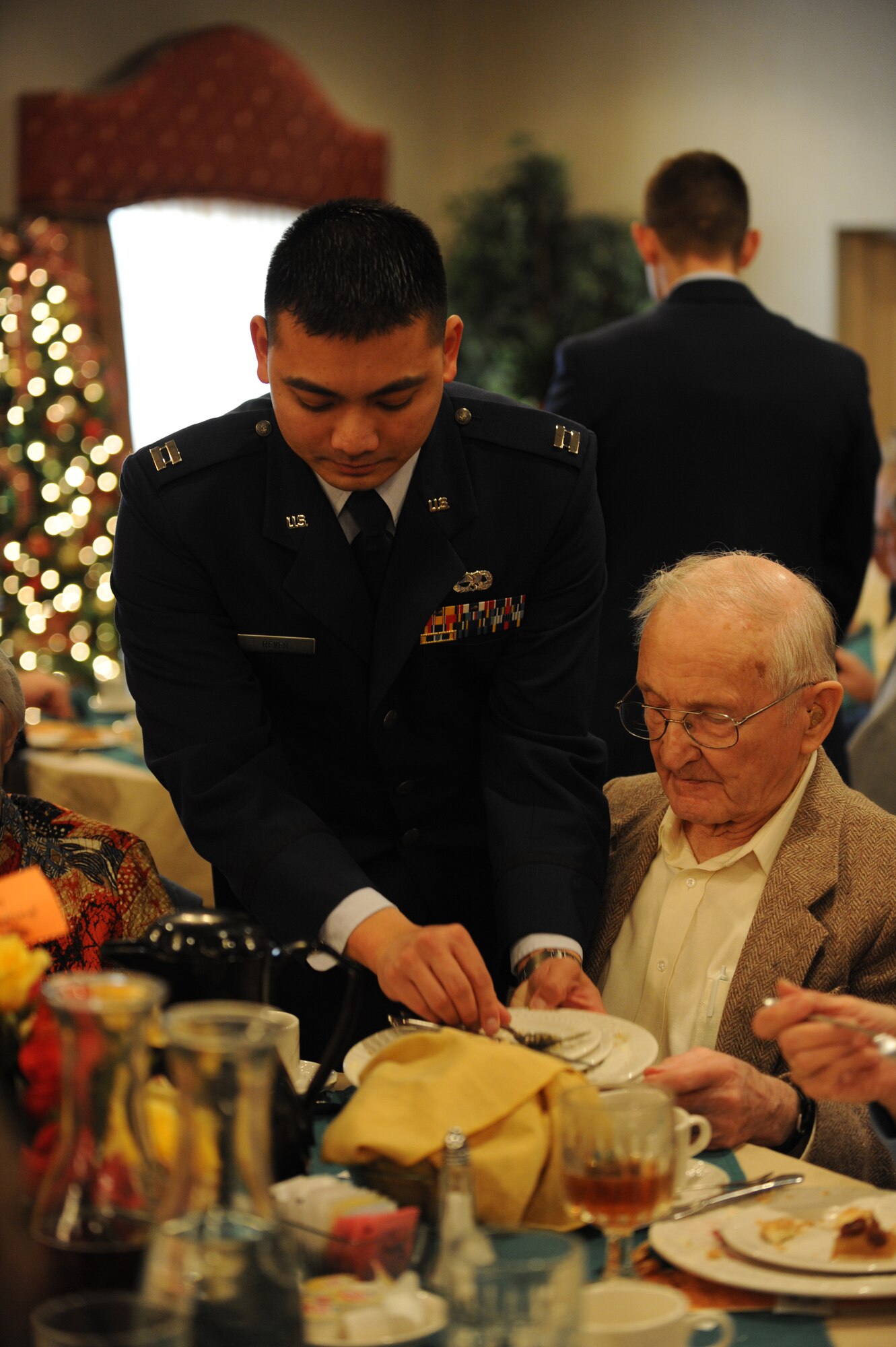 Capt. Carl Reyes, 5th Aircraft Maintenance Squadron, busses tableware during the Day of Love event at Minot Air Force Base, N.D., Nov. 28. The Thanksgiving Day tradition brings together Airmen and senior citizens from the Minot community in an afternoon of companionship and camaraderie. (U.S. Air Force photo/Senior Airman Jose L. Hernandez)