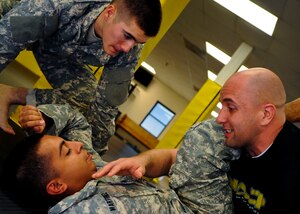 U.S. Army Staff Sgt. David Scott, right, Fort Eustis Modern Army Combatives Program instructor, teaches Sgt. Nicholas Martinez, bottom left, and Pvt. Cameron Johnson, both MACP students, how to move into a side position during MACP training at Fort Eustis, Va., Nov. 18, 2013. Scott spends most of his free time either training with his son, teaching classes after work or training to improve his muay thai and Brazilian jiu-jitsu. (U.S. Air Force photo by Airman 1st Class Austin Harvill/Released)