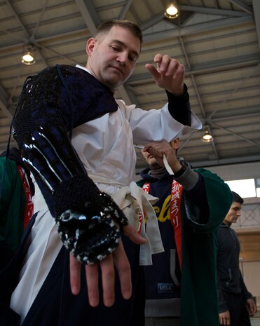 Sgt. Justin Pack, operations chief with the station Public Affairs Office, receives help with the placement of his samurai armor inside the Kuga Elementary School Gym before the start of the Kuragake Castle Festival Nov. 17, 2013. Marines from Marine Corps Air Station Iwakuni, Japan, donated their time to volunteer in the festival.