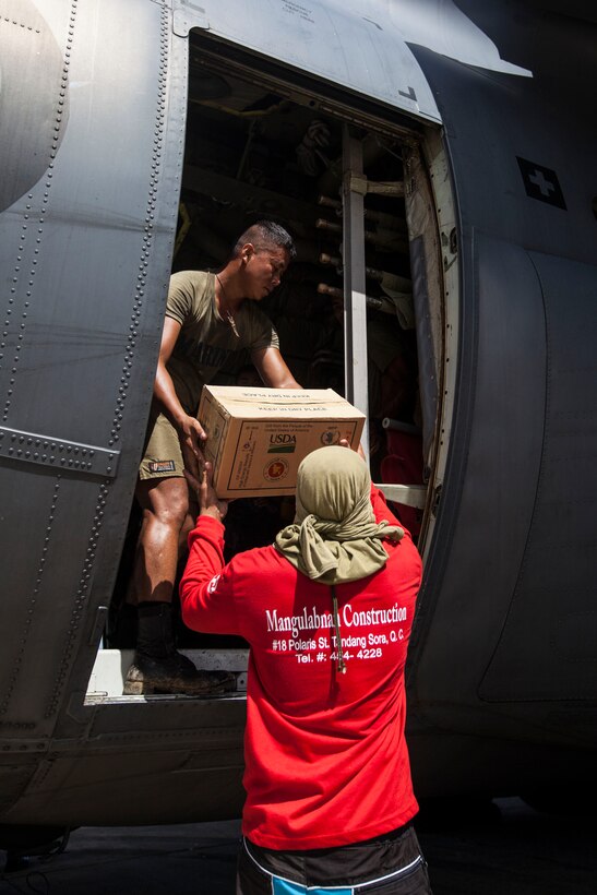 A Philippine Marine hands a box of supplies to a Filipino volunteer from the door of a C-130 Hercules aircraft from the Royal New Zealand Air Force here, Nov. 25. The combined Philippine and international effort delivered more than 79,000 lbs. of rice and high-energy biscuits to eight island villages. The 31st Marine Expeditionary Unit, deployed with 3D Marine Expeditionary Brigade, in support of Joint Task Force 505, is currently supporting the government of the Philippines during Operation Damayan by assisting with disaster relief efforts in areas affected by Super Typhoon Haiyan/Yolanda. 