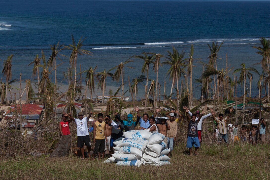 Filipinos express their gratitude after dozens of bags of rice were offloaded from an MV-22 Osprey with Marine Medium Tiltrotor Squadron 265, 31st Marine Expeditionary Unit (MEU), during a supply drop-off at a village here, Nov. 25. The combined Philippine and international effort delivered more than 79,000 lbs. of rice and high-energy biscuits to eight island villages. The 31st MEU, deployed with 3D Marine Expeditionary Brigade, in support of Joint Task Force 505, is currently supporting the government of the Philippines during Operation Damayan by assisting with disaster relief efforts in areas affected by Super Typhoon Haiyan/Yolanda. 